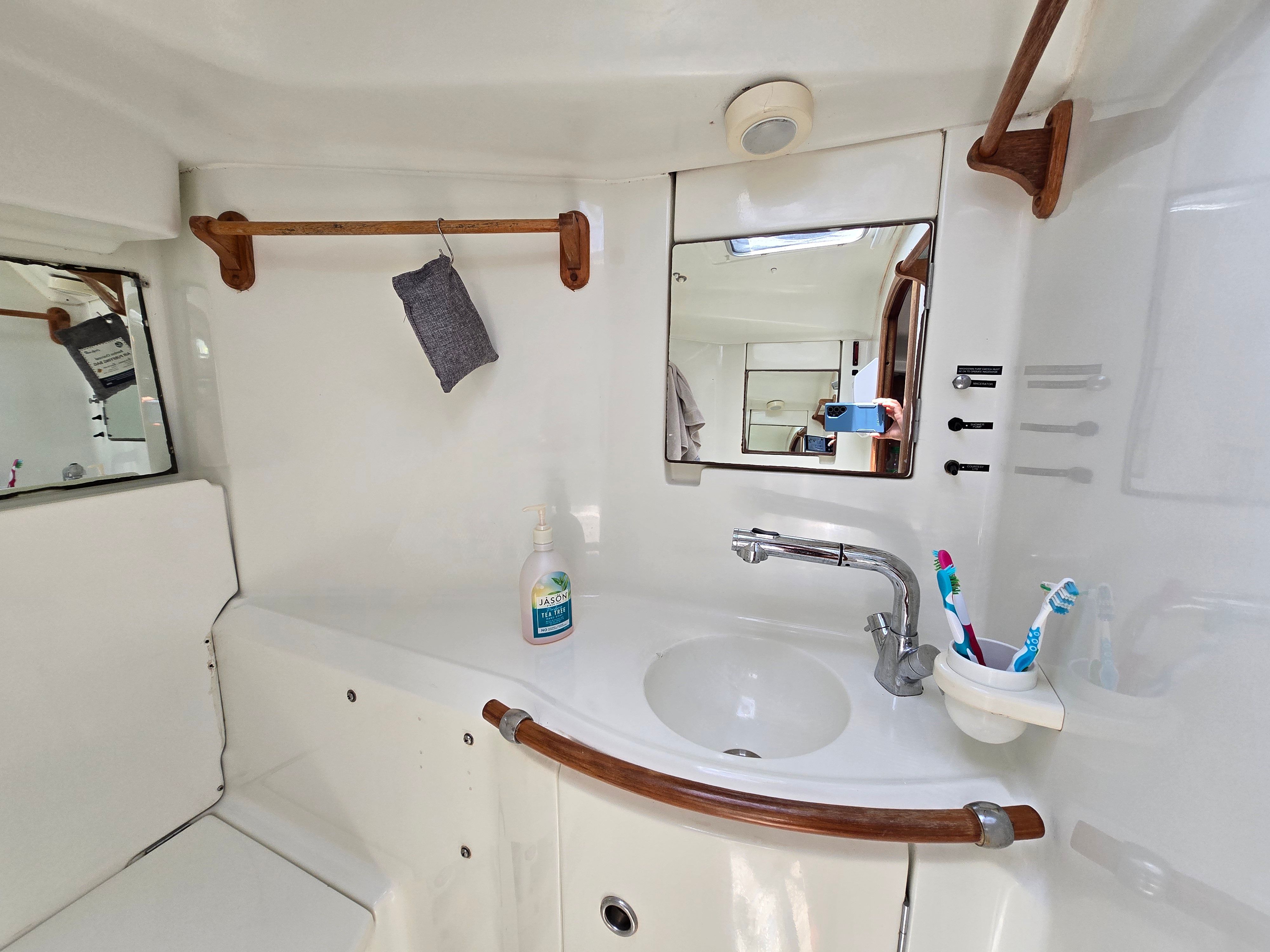 Interior view of a boat bathroom with sink, mirror, and toothbrush holder.