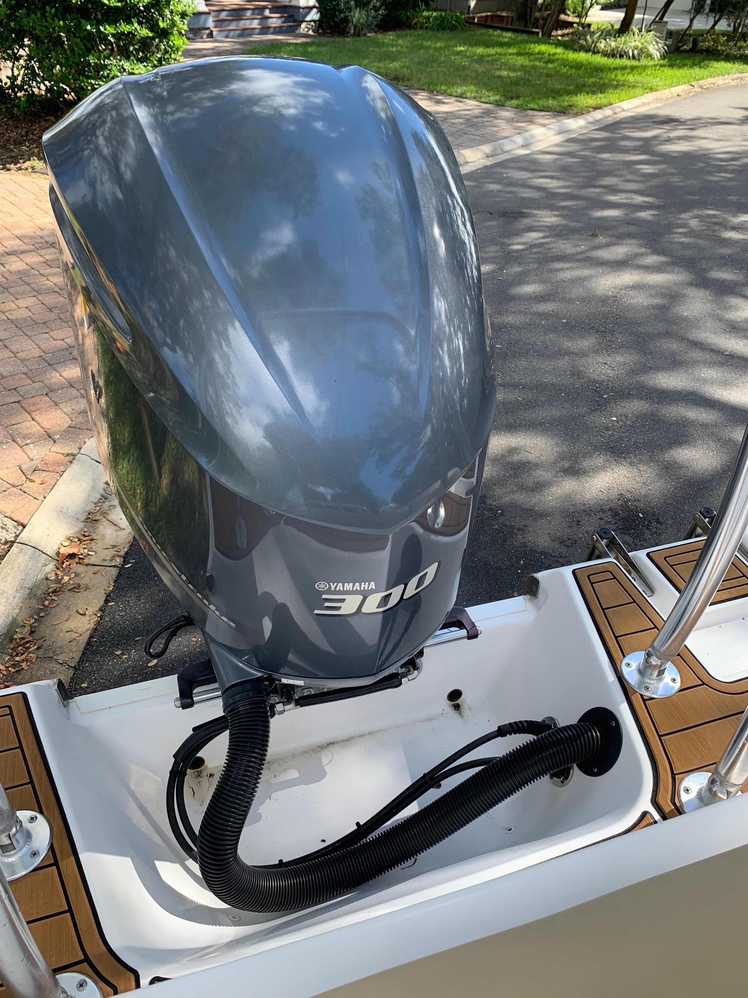 A Yamaha 300 outboard motor on a boat, situated on a paved path.