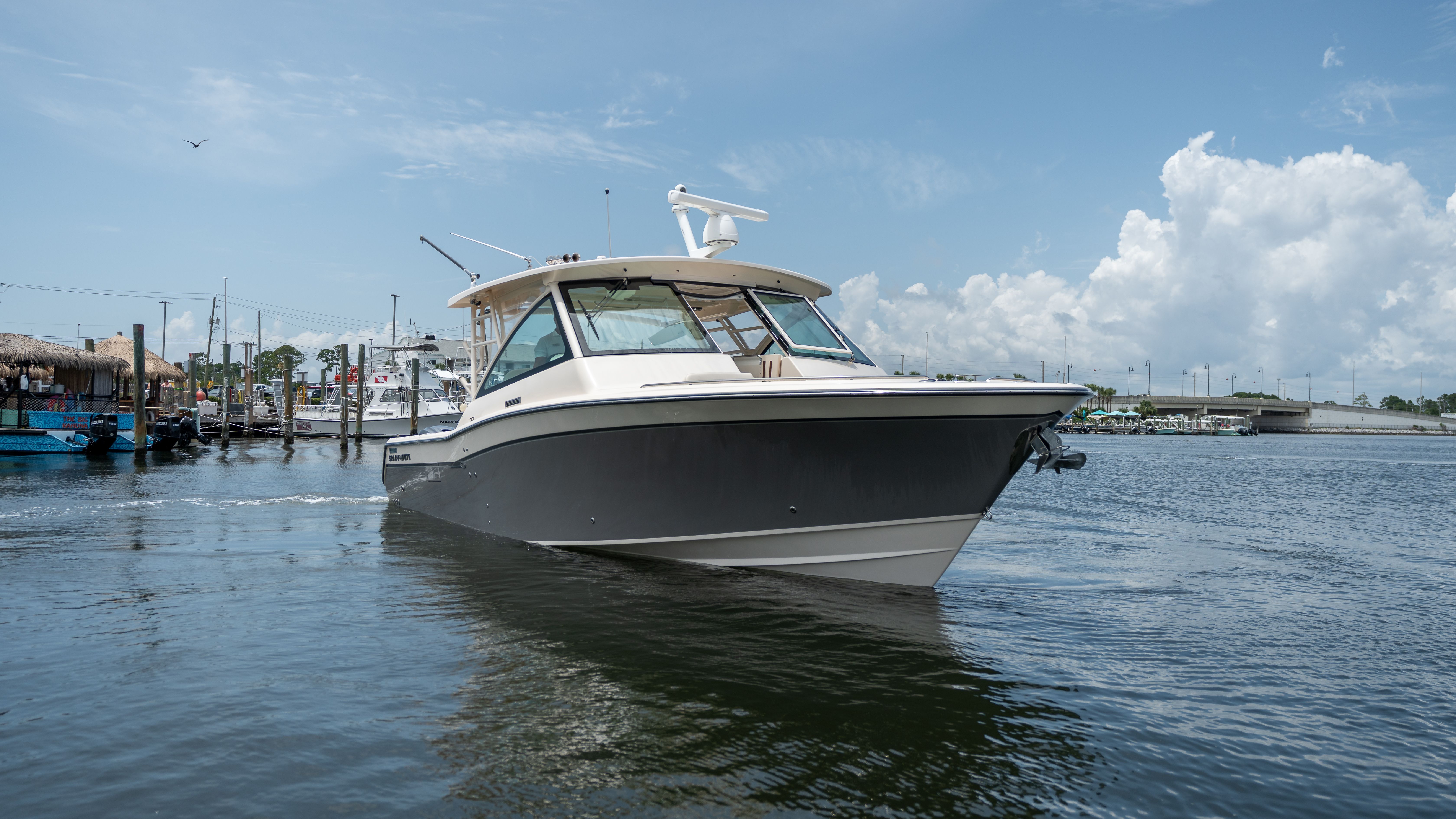 2019 Grady-White 375 Freedom on calm water, surrounded by a marina and blue sky.