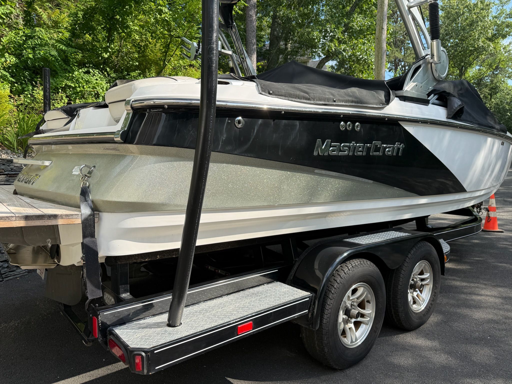 A 2013 MasterCraft X-25 boat on a trailer, surrounded by trees.