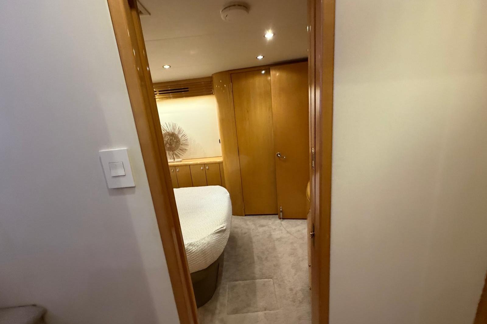 Interior of 2003 Hatteras 54 Convertible yacht bedroom with wooden cabinetry.