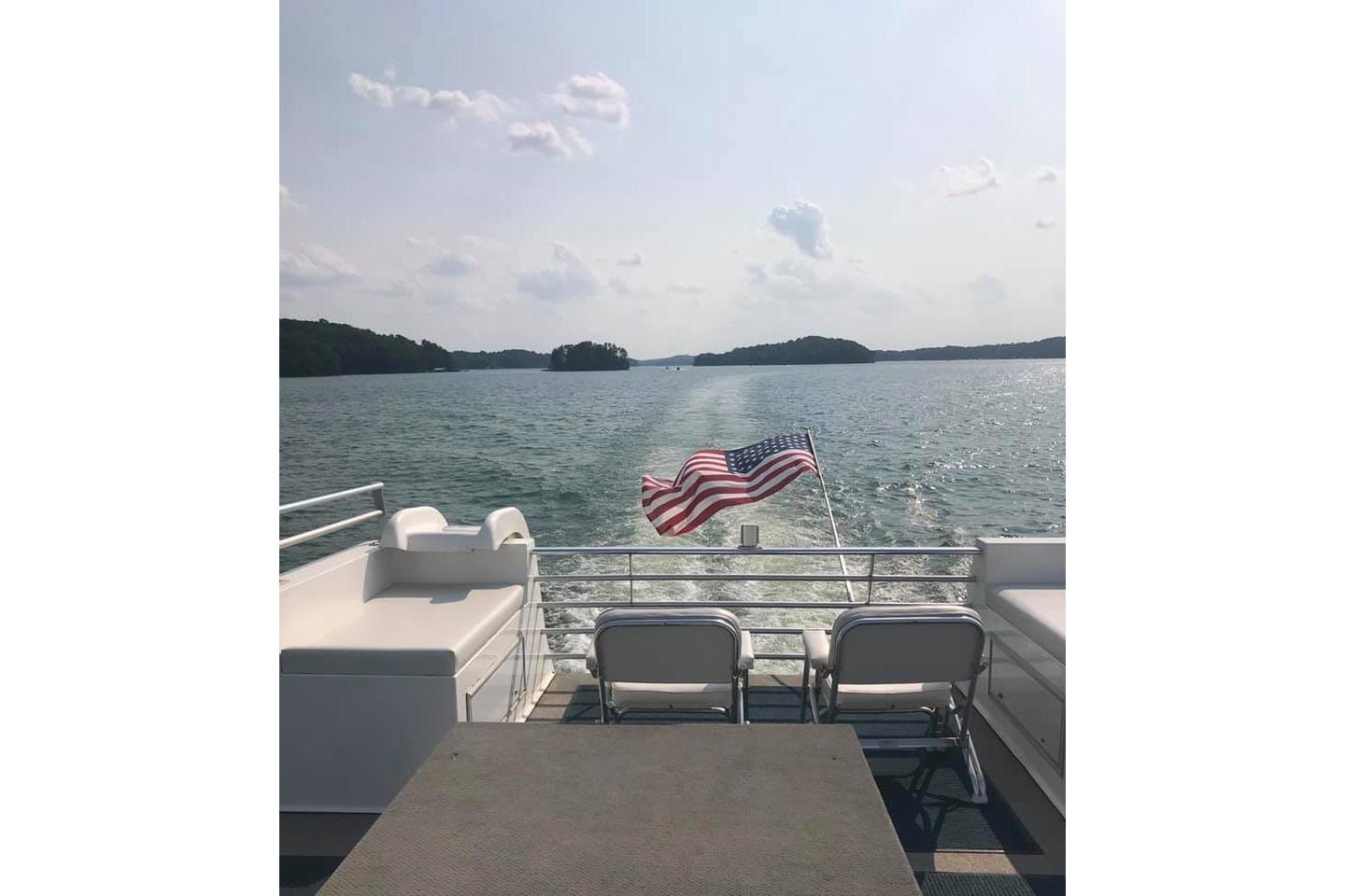2008 Destination Yachts 45X14 on a lake, American flag waving, sunny day.