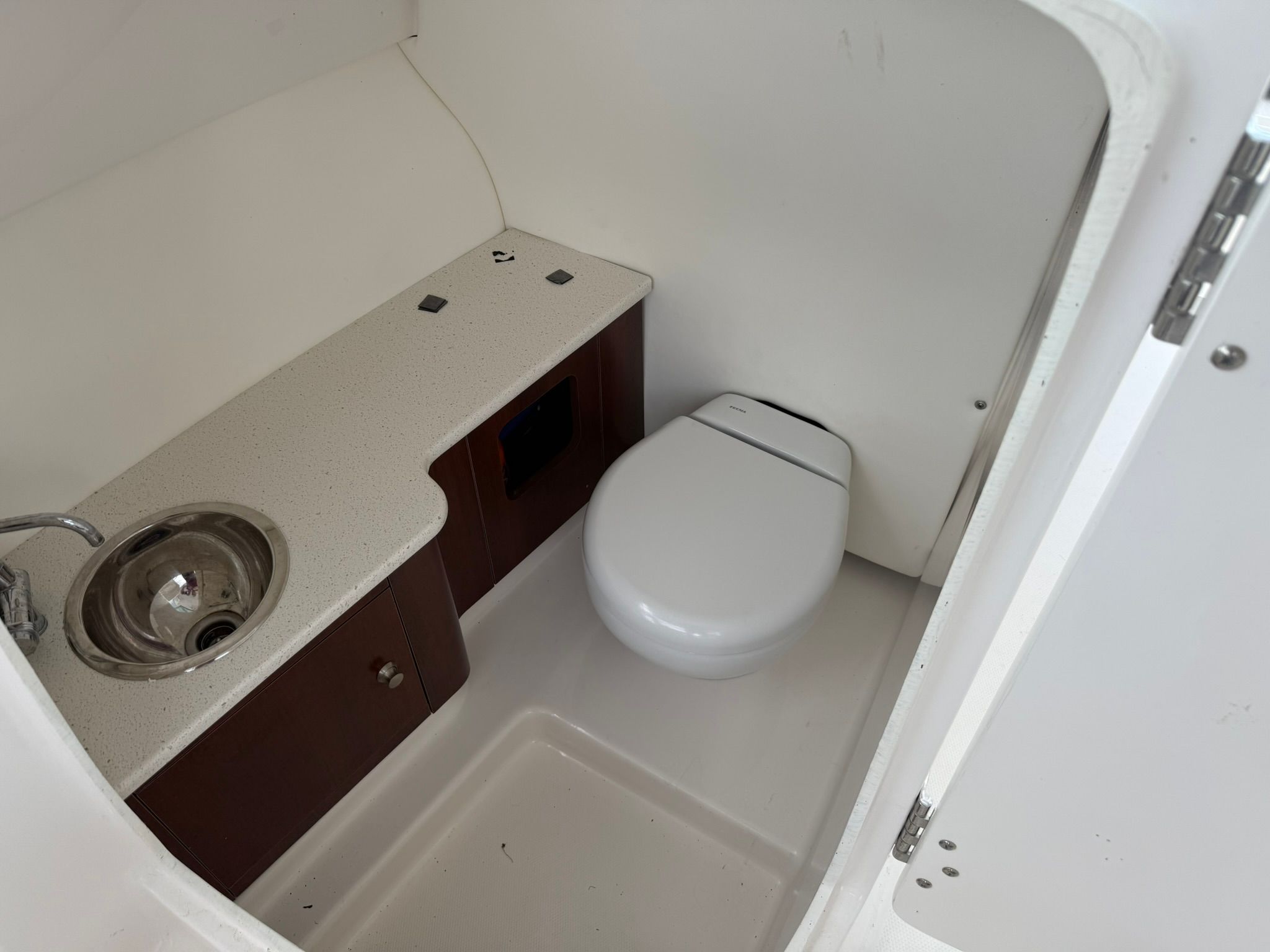Interior view of a boat bathroom with a sink, toilet, and storage space.