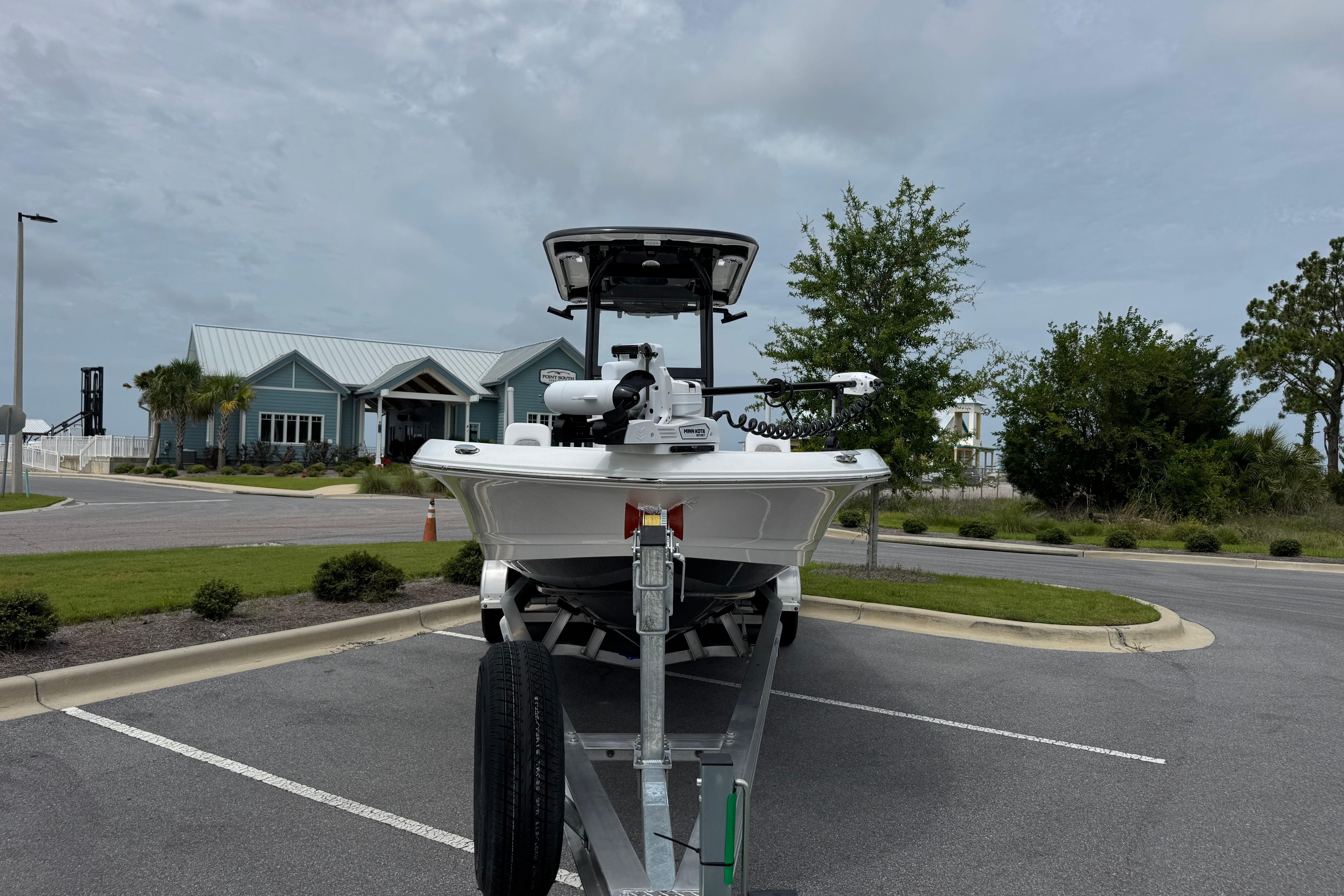 2027 Caymas 26 HB boat on trailer in parking lot, cloudy sky background.