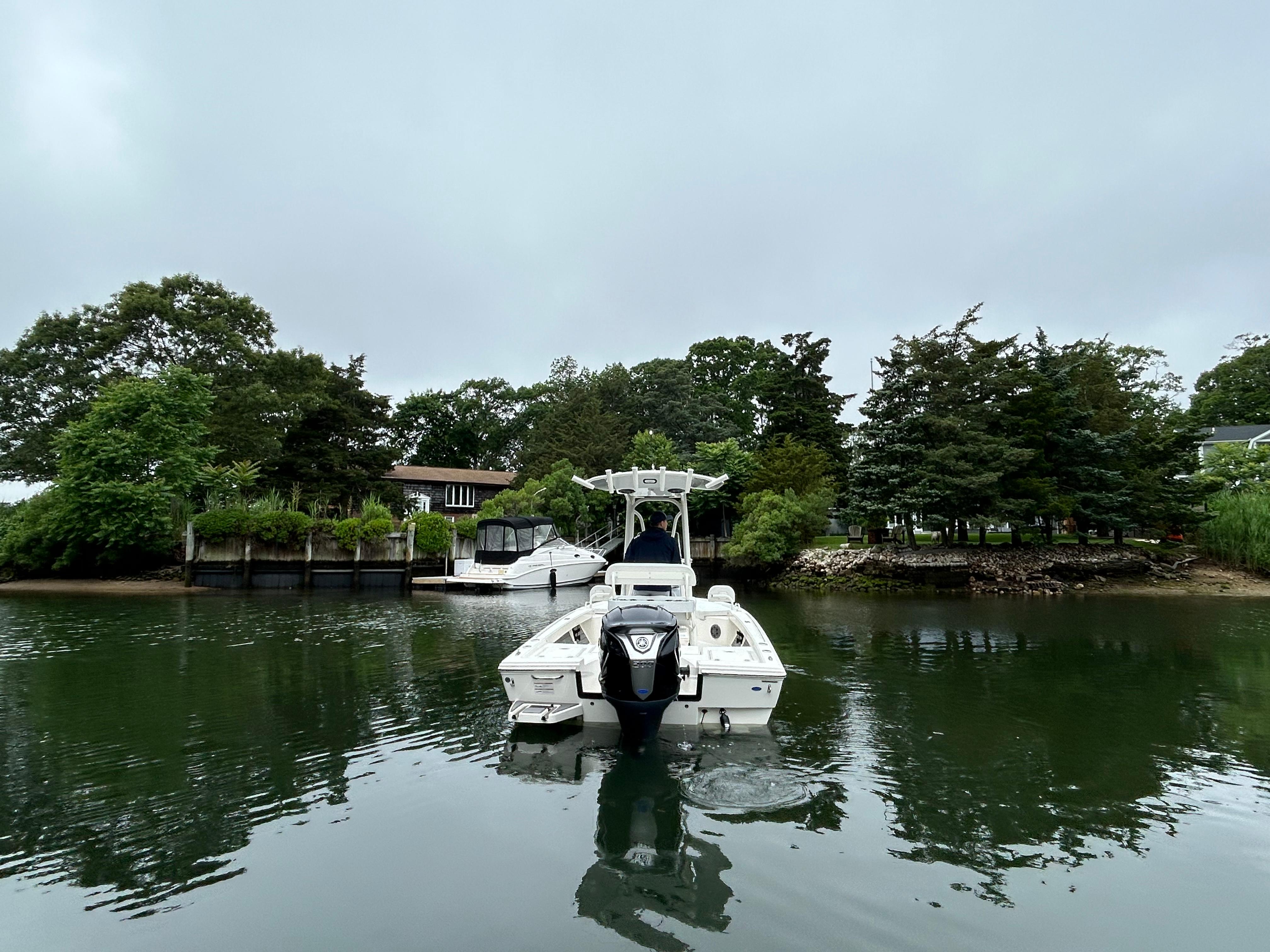 2024 Pathfinder 2200 TRS boat on calm water near lush greenery and docked vessels.