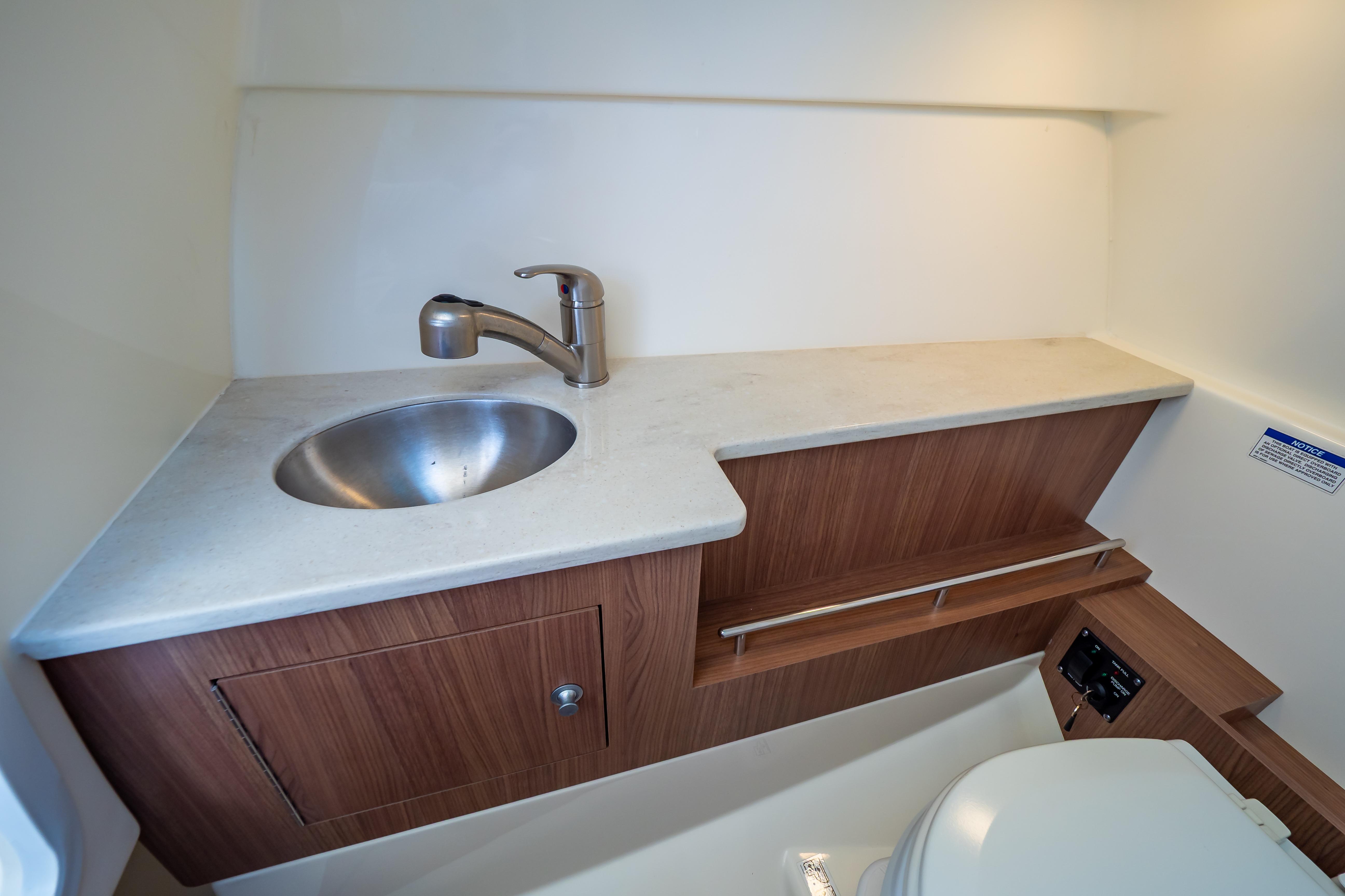 2019 Boston Whaler 270 Vantage boat bathroom with sink and wooden cabinetry.