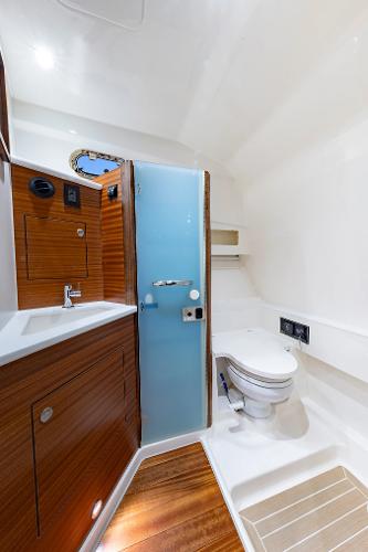 2025 Pursuit OS 405 yacht bathroom with wooden cabinetry and modern fixtures.