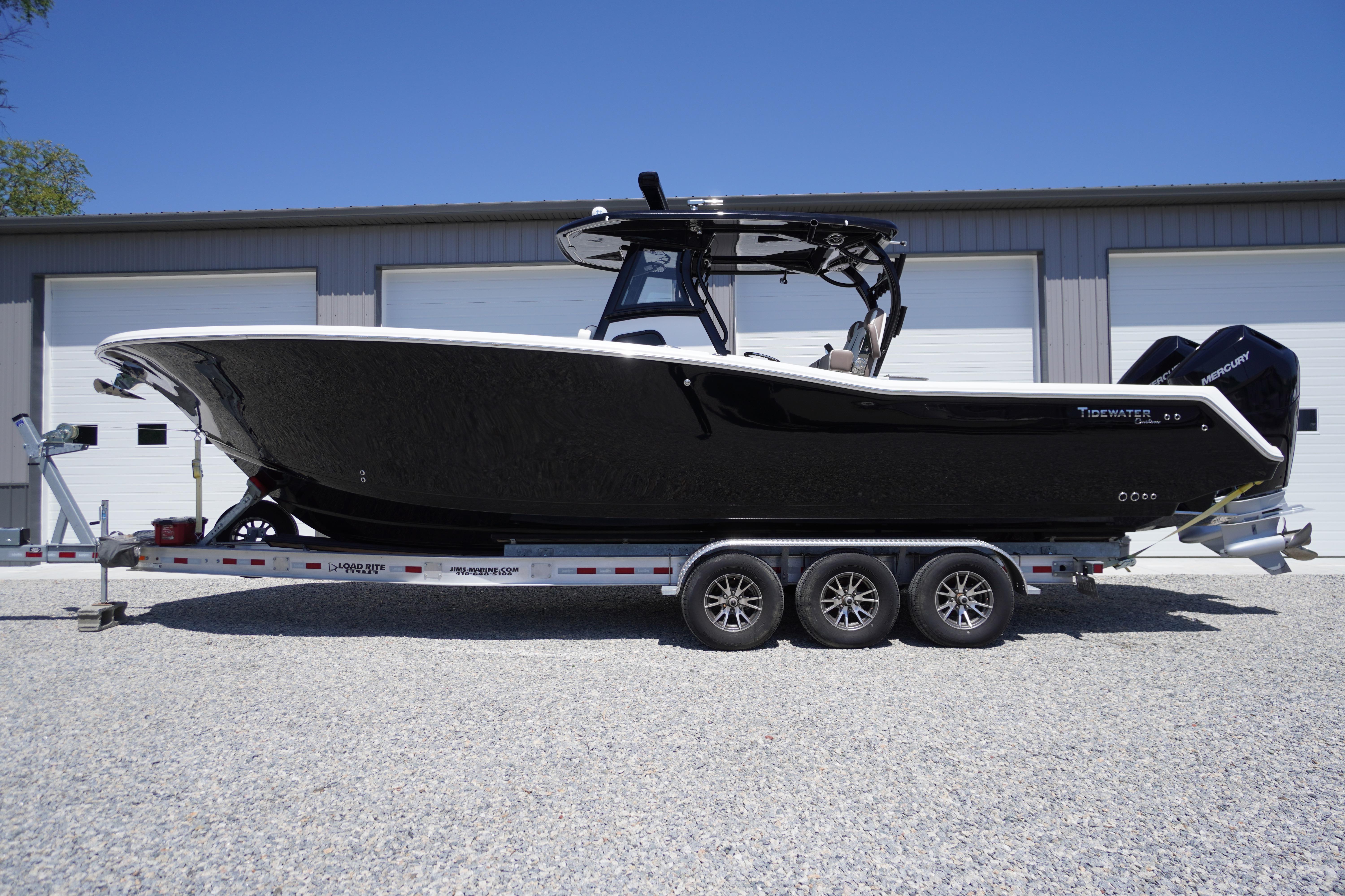 2024 Tidewater 320 CC Adventure boat on trailer, black hull, parked outdoors.