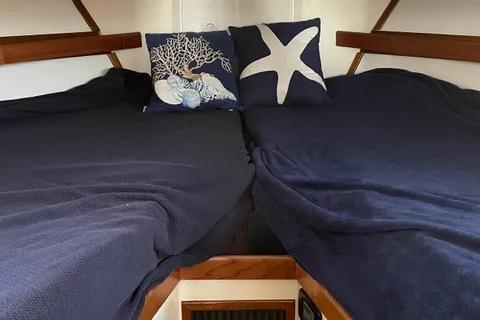 Cozy cabin interior of a 1997 Rosborough Trawler with nautical-themed pillows.