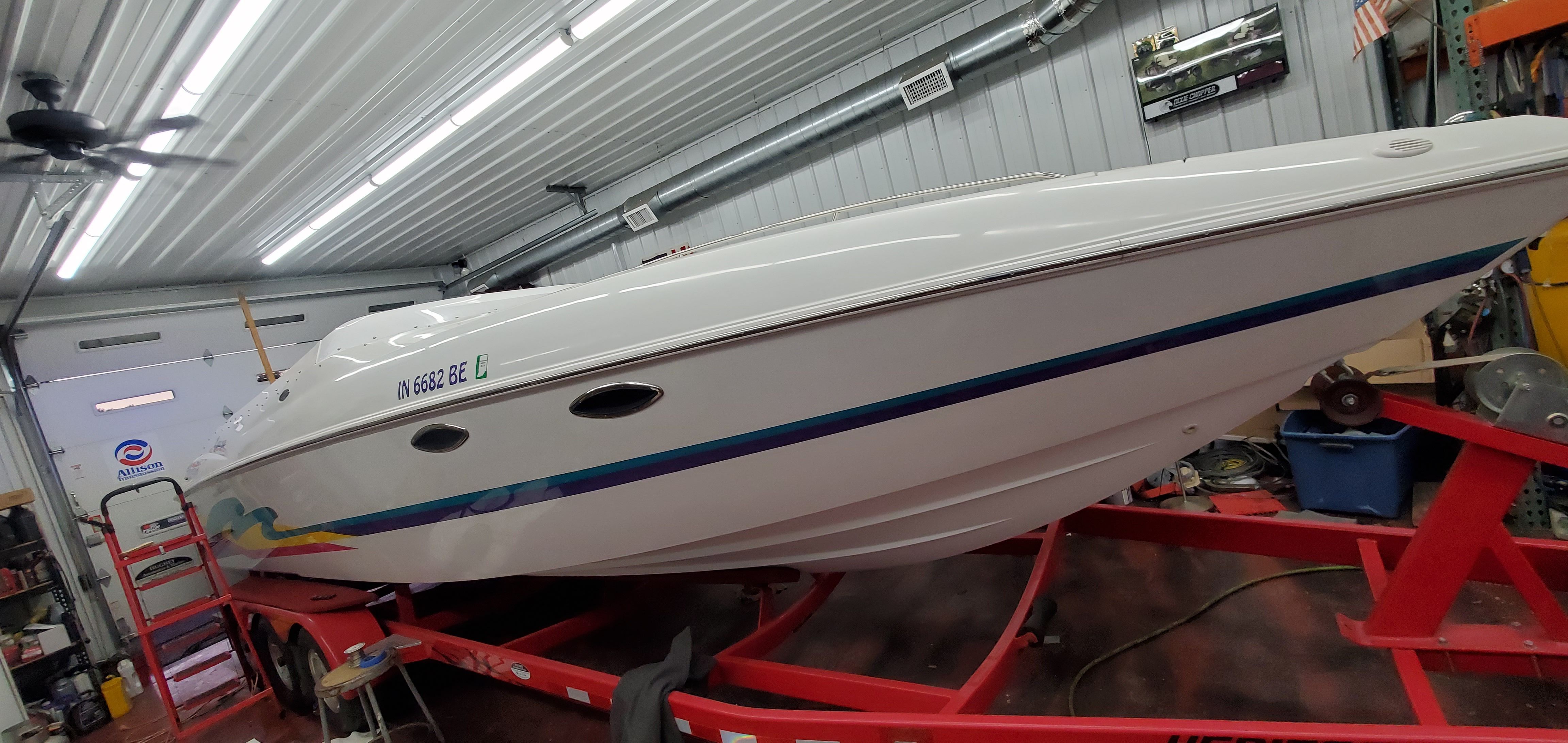 A white 1996 Baja 302 Boss boat sits on a red trailer in a garage.