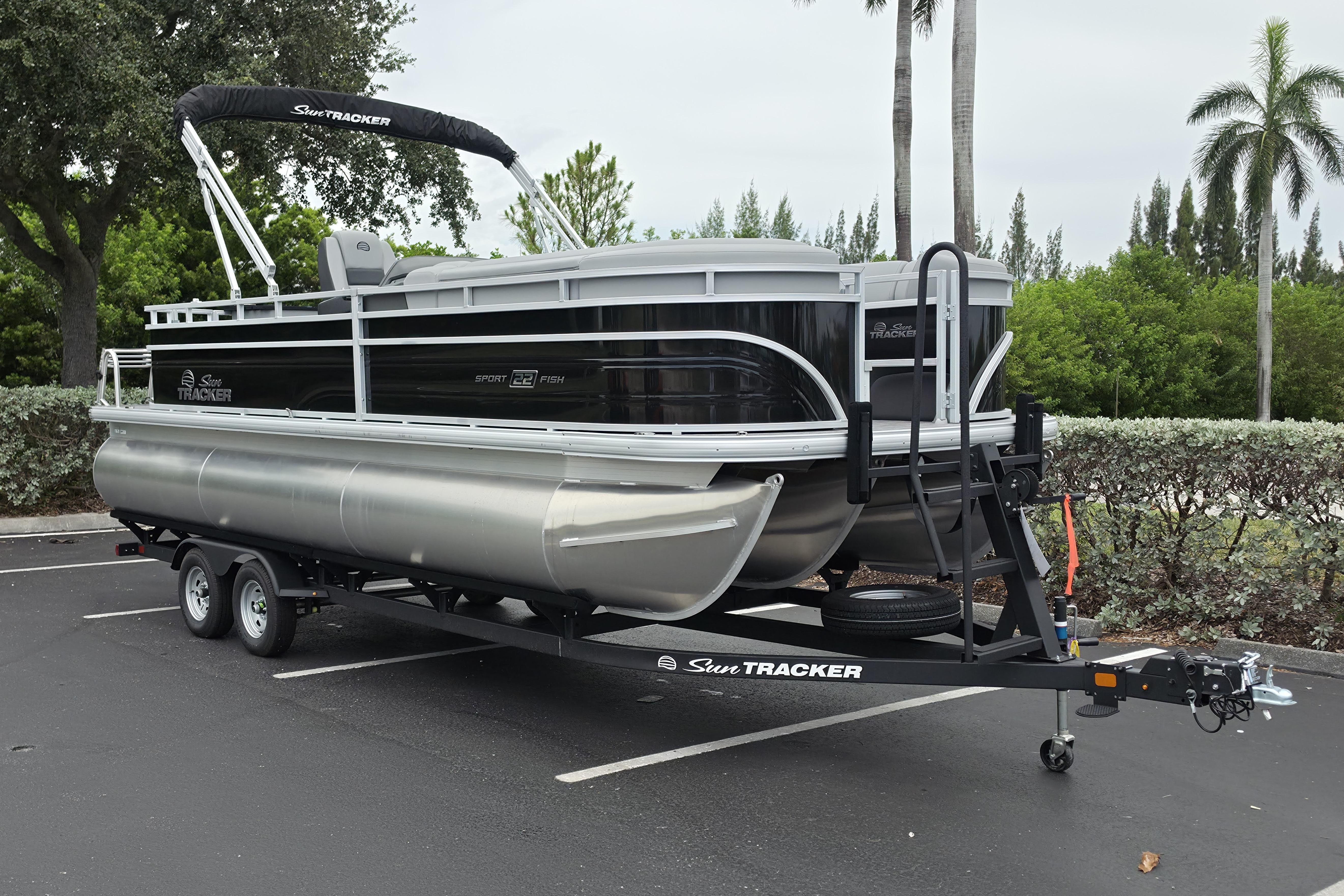 2026 Sun Tracker SportFish 22 XP3 pontoon boat on trailer in parking lot.