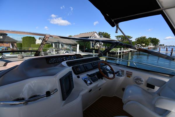 1997 Sea Ray 400 Sundancer helm with waterfront view, featuring steering wheel and control panel.