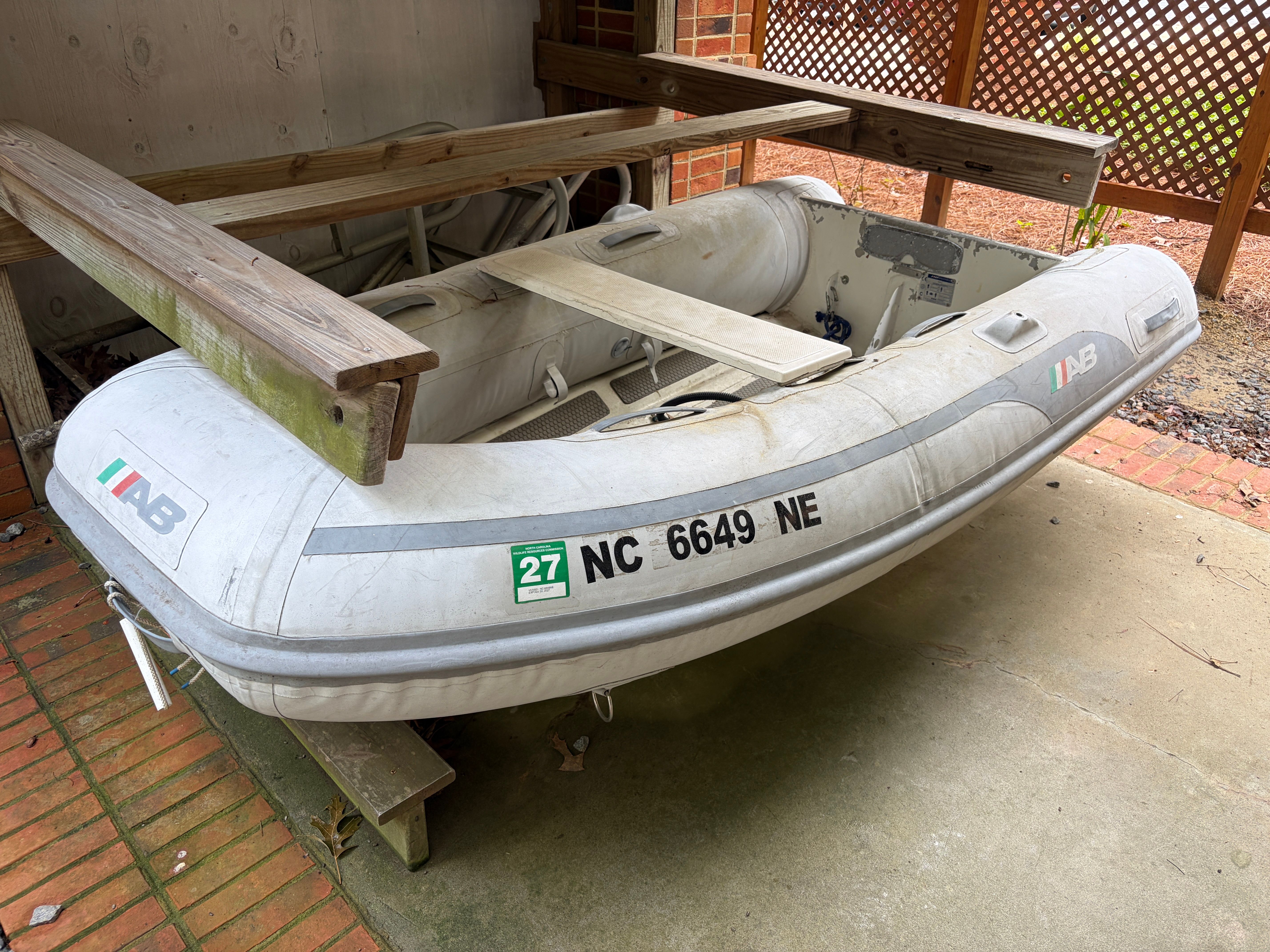 An inflatable boat with a wooden frame and registration number, resting on a concrete floor.