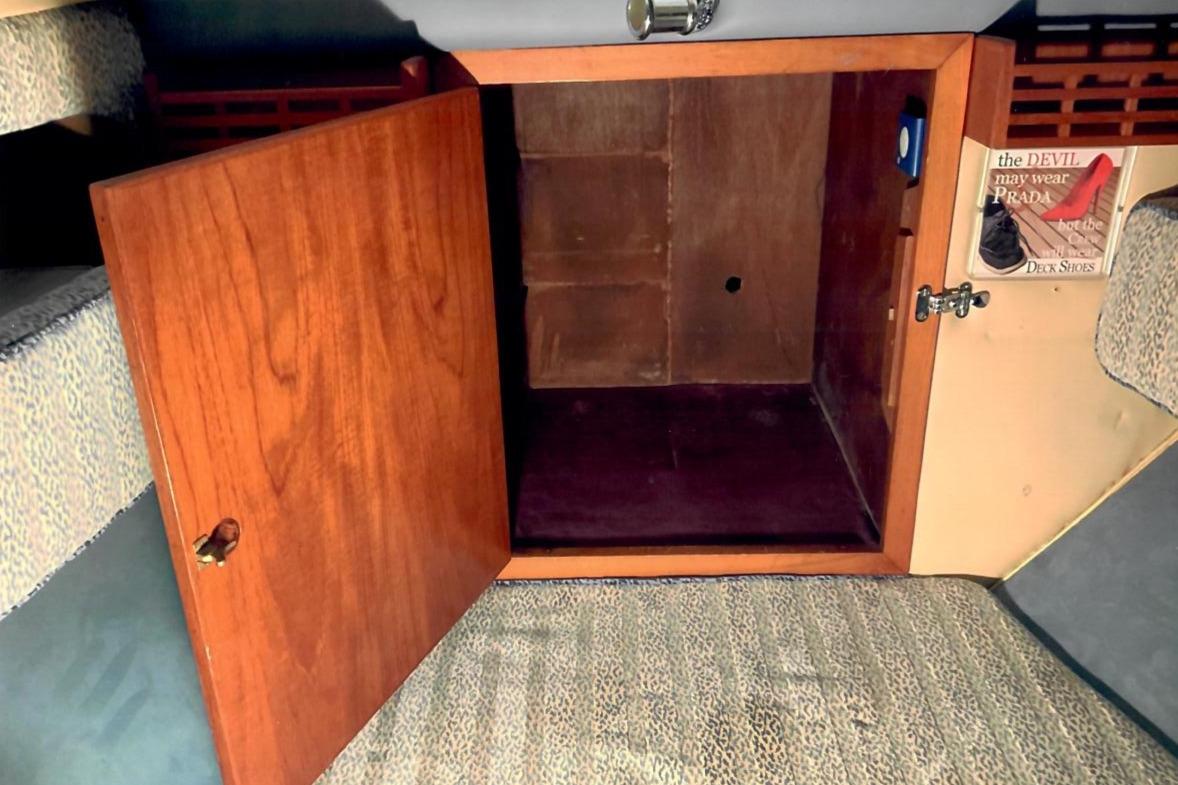 Open wooden cabinet inside 1989 Fairey Spearfish MKIII boat, with patterned carpet flooring.