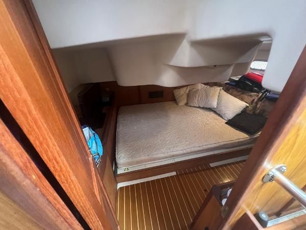 Interior of a 2000 Hunter 410 with a cozy bed and wooden flooring.