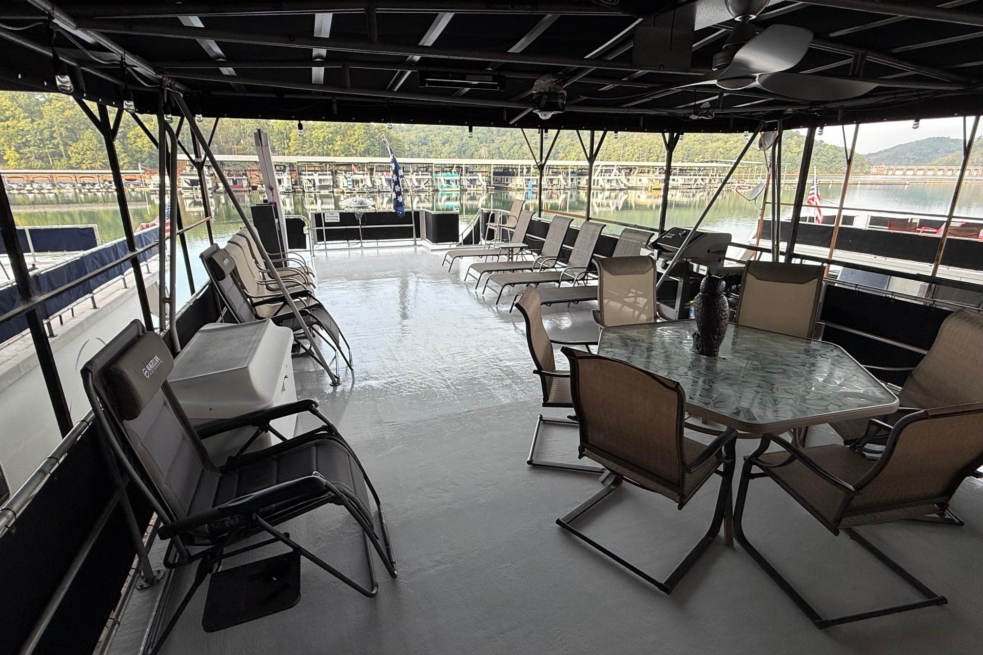 Spacious deck of 1998 Sumerset 16x76 houseboat with seating and scenic marina view.