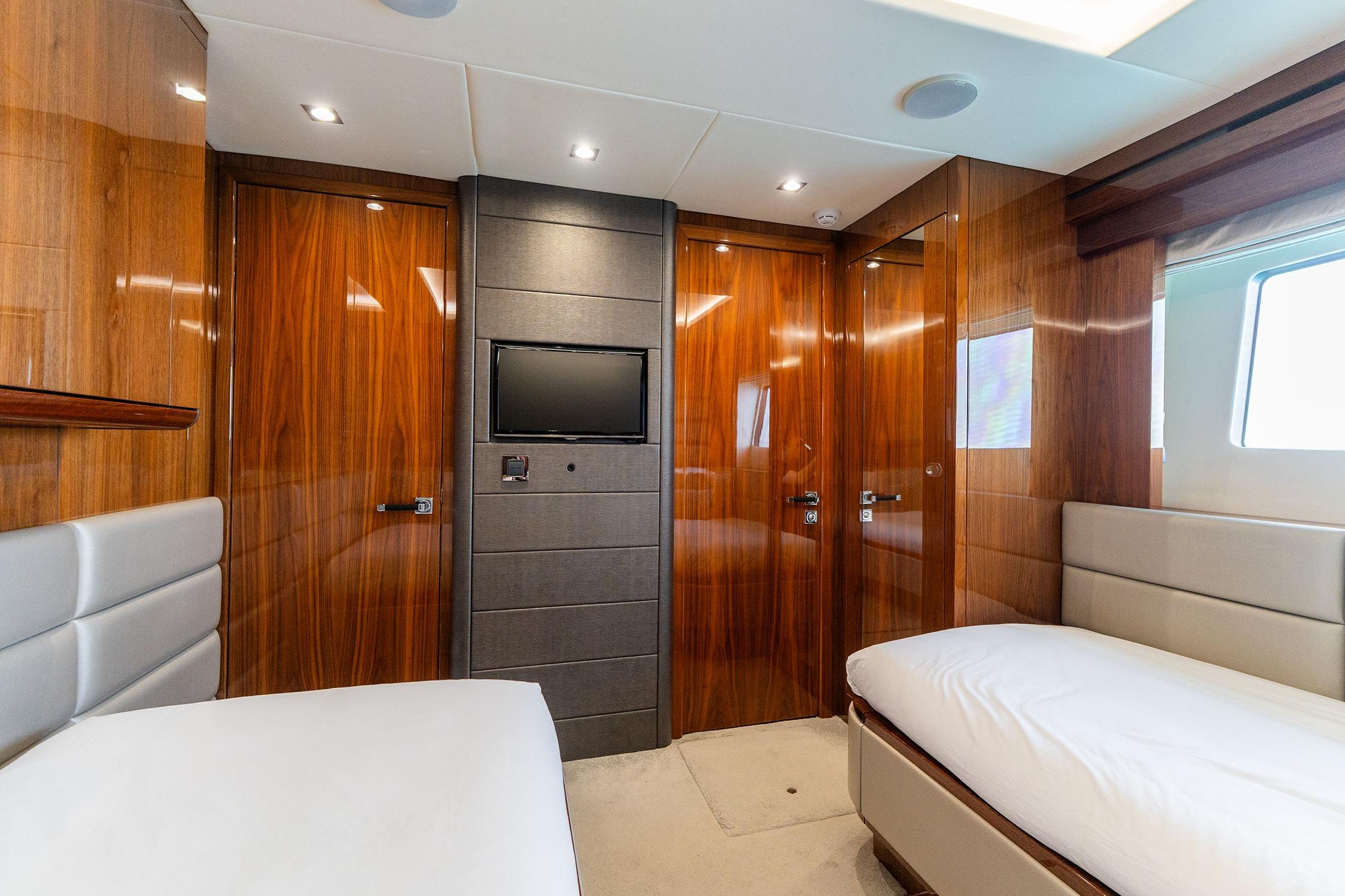 Luxurious cabin interior of 2015 Sunseeker 86 Yacht with wood paneling and twin beds.