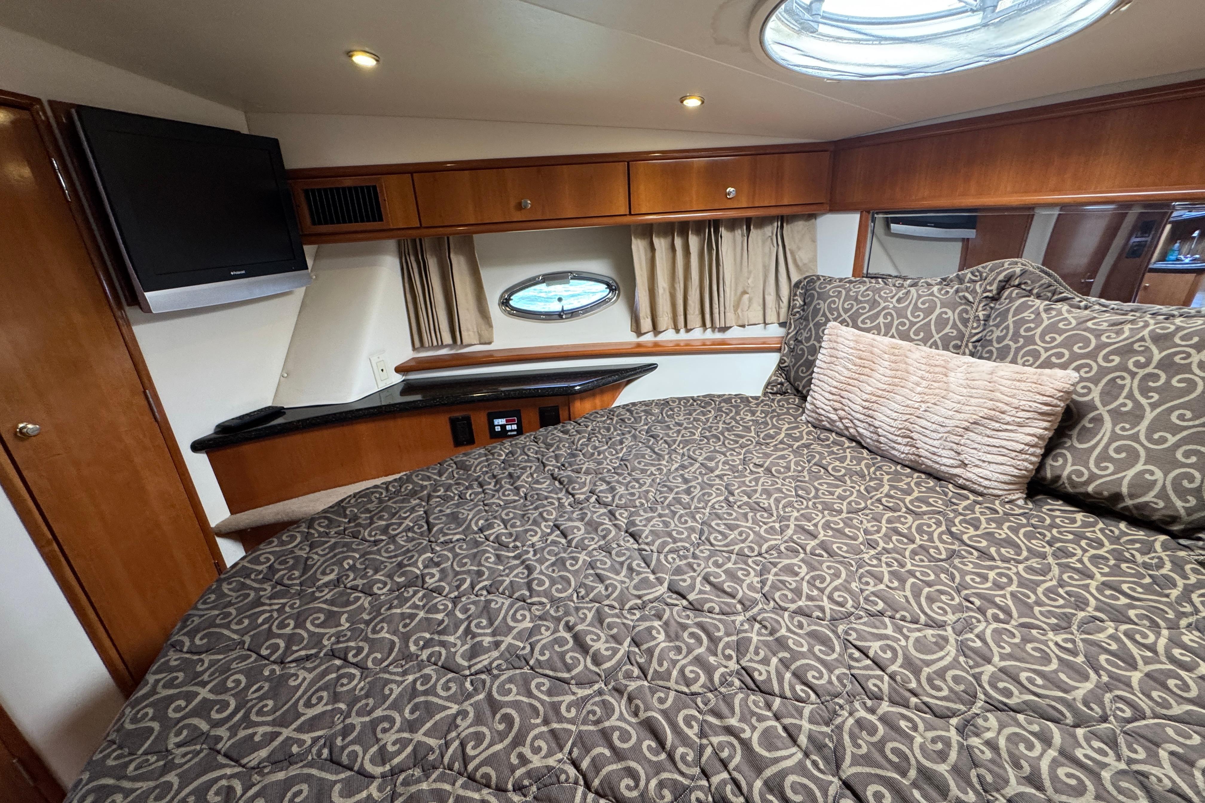 Luxurious interior of 2002 Carver 396 Motor Yacht with cozy bedding and elegant wood finishes.