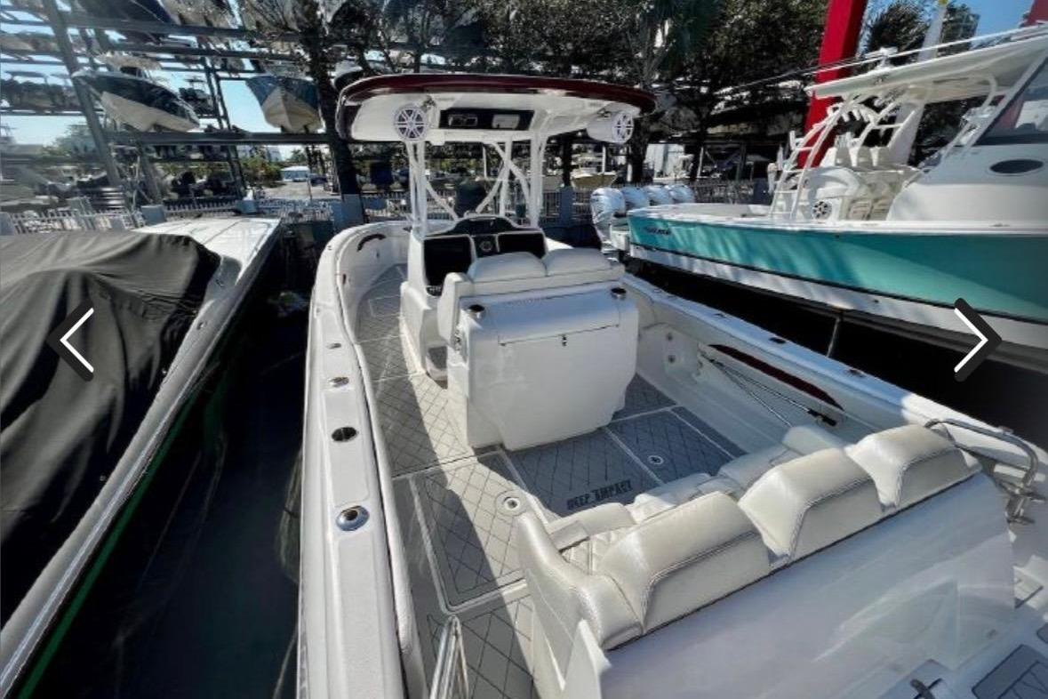 2015 Deep Impact 33 boat with white seating, docked among other boats.