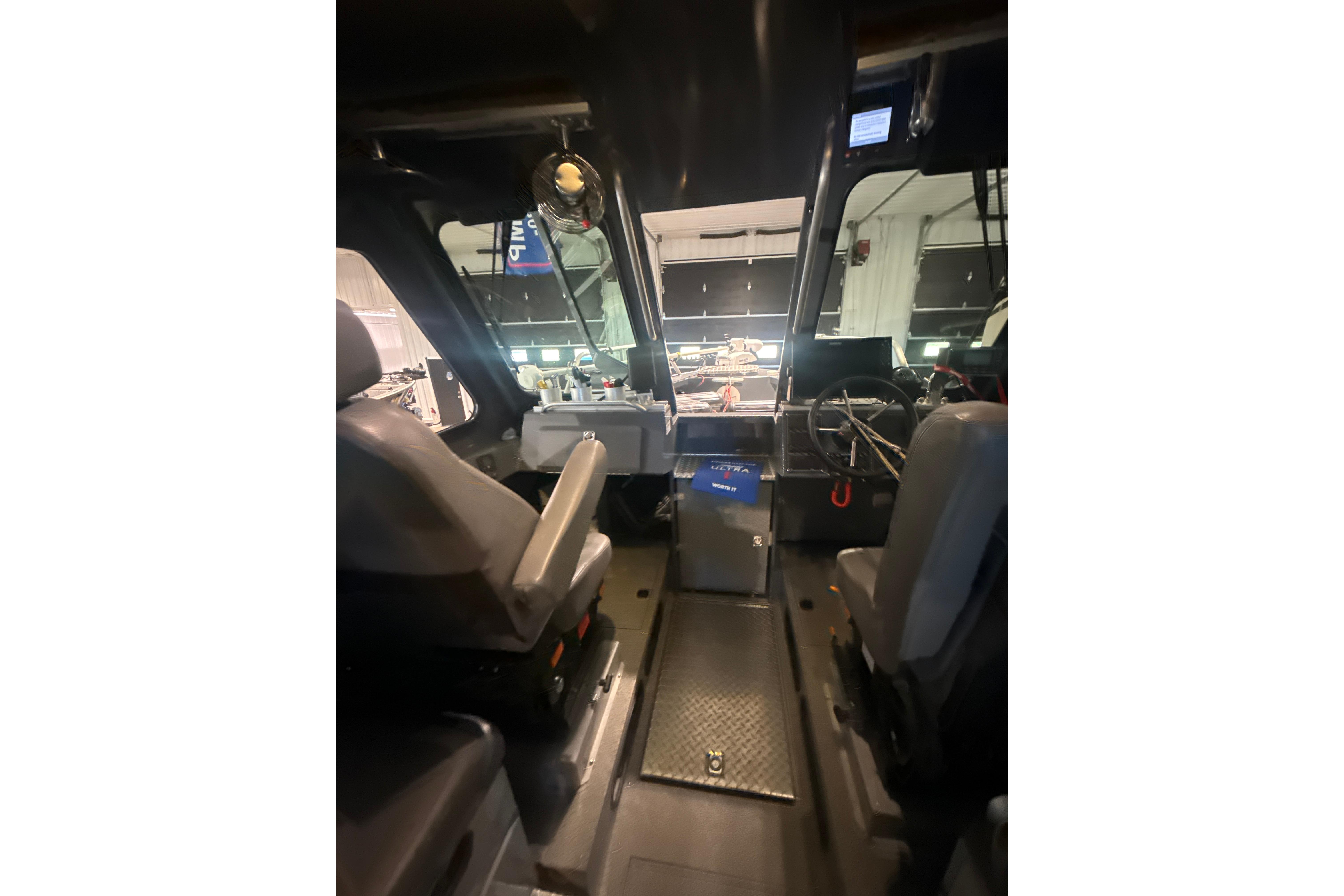 Interior view of 2022 Hewescraft 270 Alaskan Hardtop boat cockpit with seating and controls.
