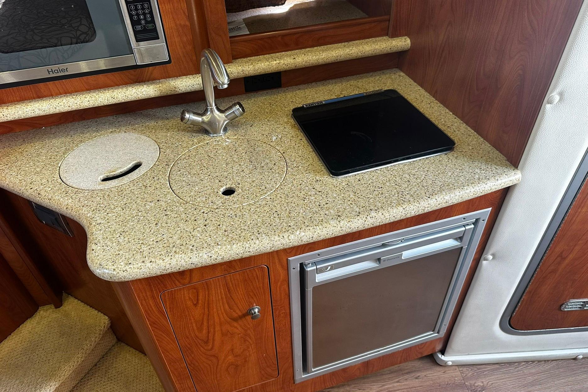 2012 Rinker 310 Express Cruiser LE kitchenette with sink, microwave, and mini-fridge.