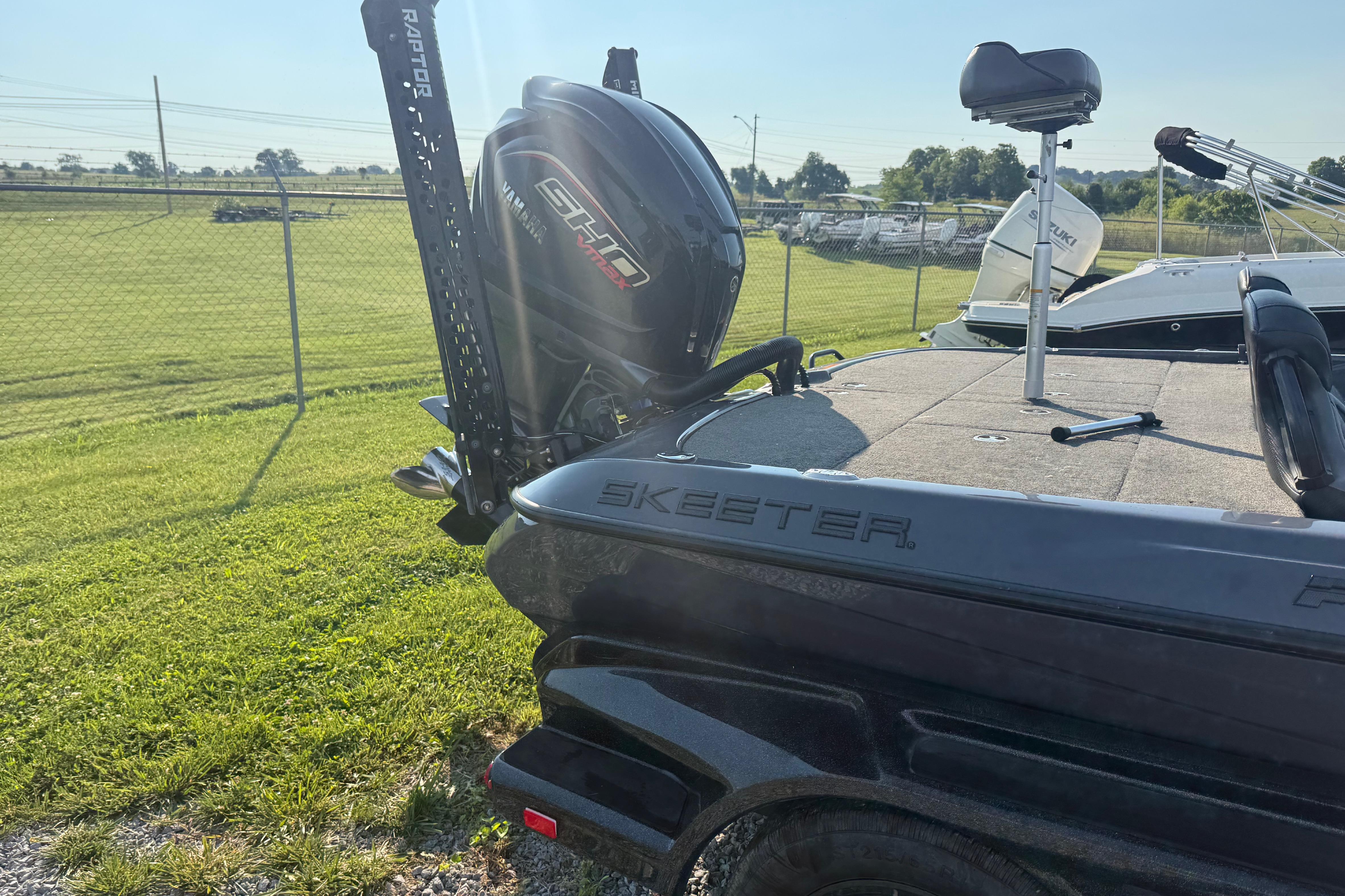 2024 Skeeter FXR21 boat with Yamaha engine, parked on grass near a fence.