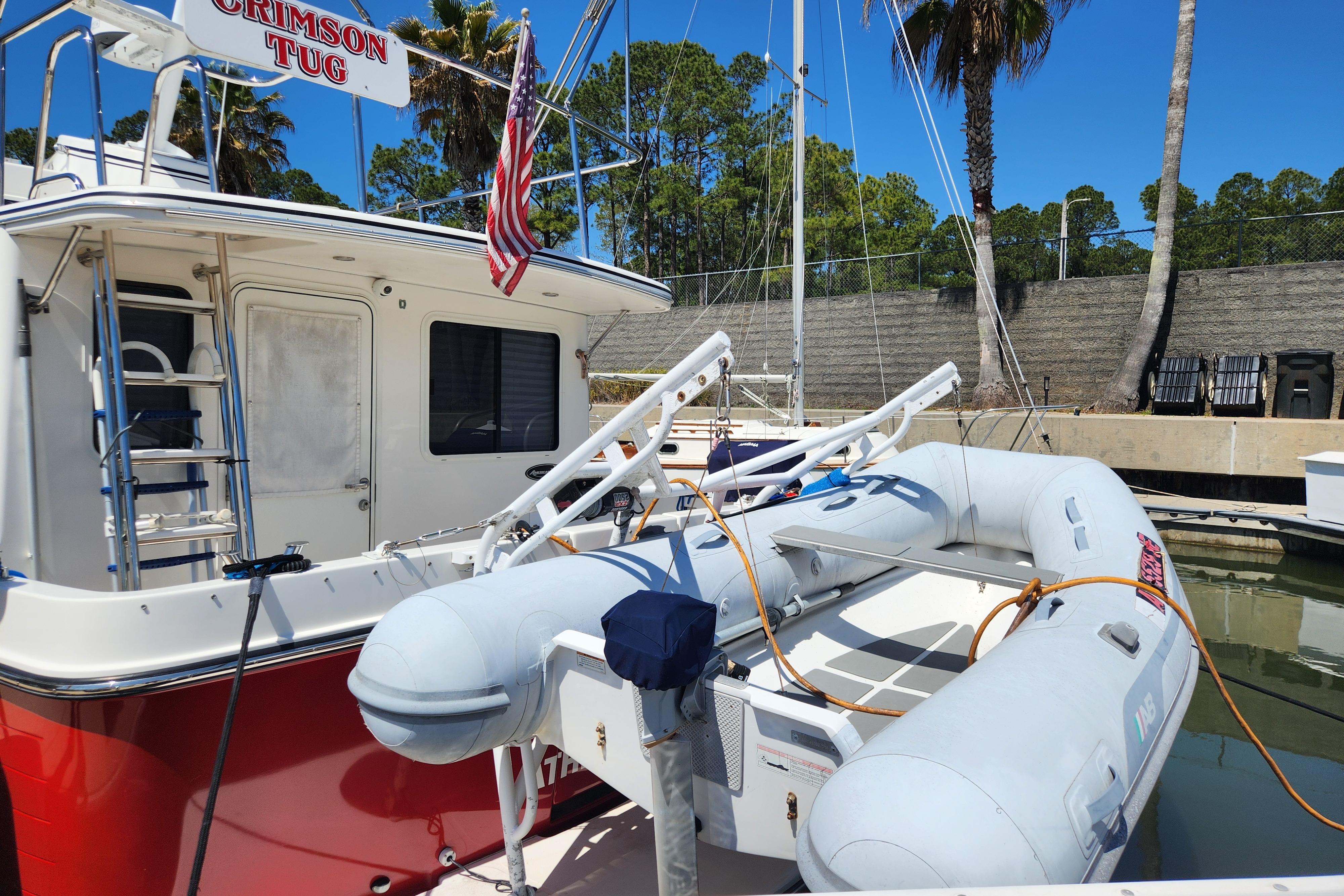 American Tug AT 2006 docked with inflatable boat, displaying American flag.