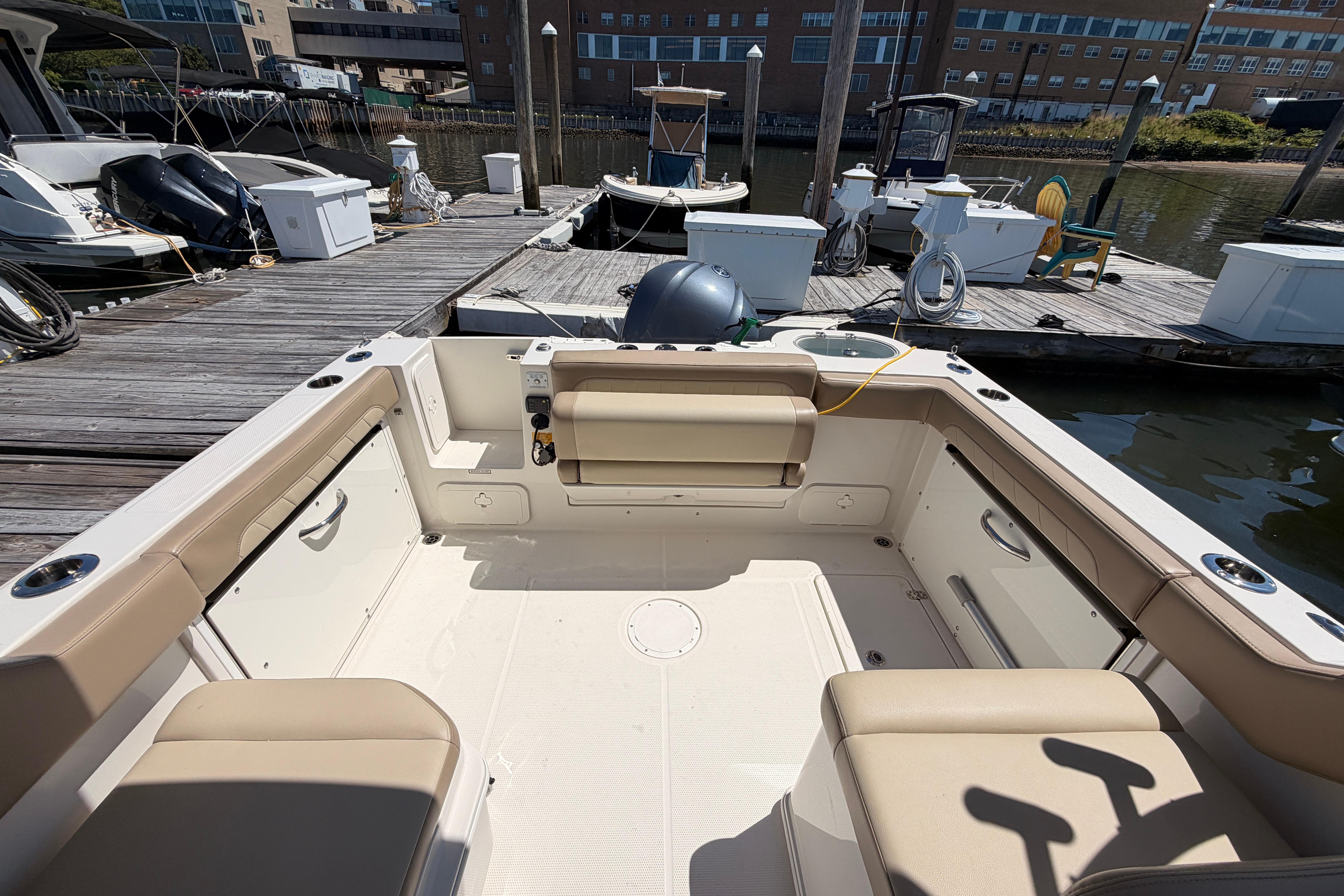 2019 Sailfish 245 DC boat interior at dock, featuring beige seating and spacious layout.
