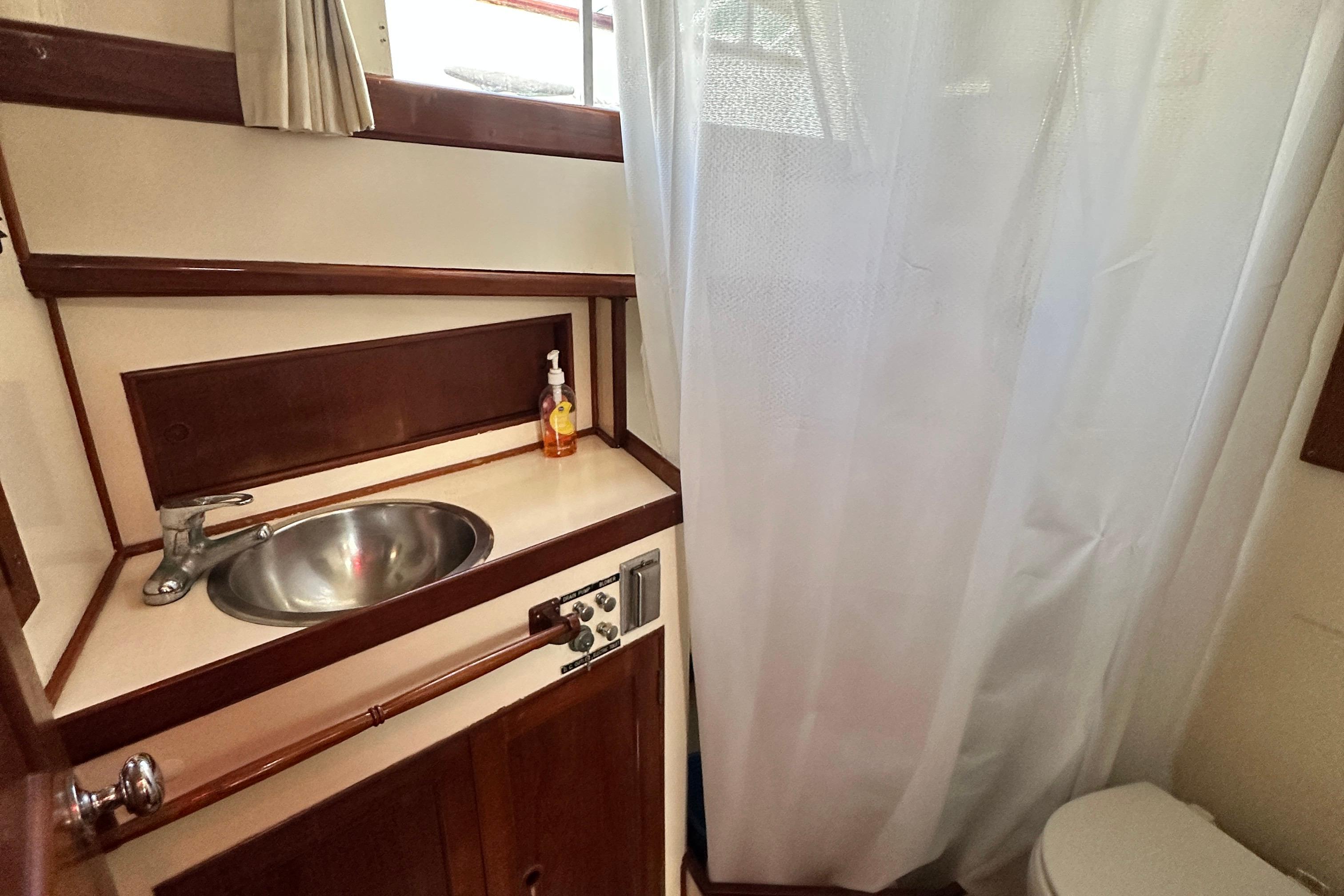 1980 Island Gypsy yacht bathroom with sink, faucet, and shower curtain.