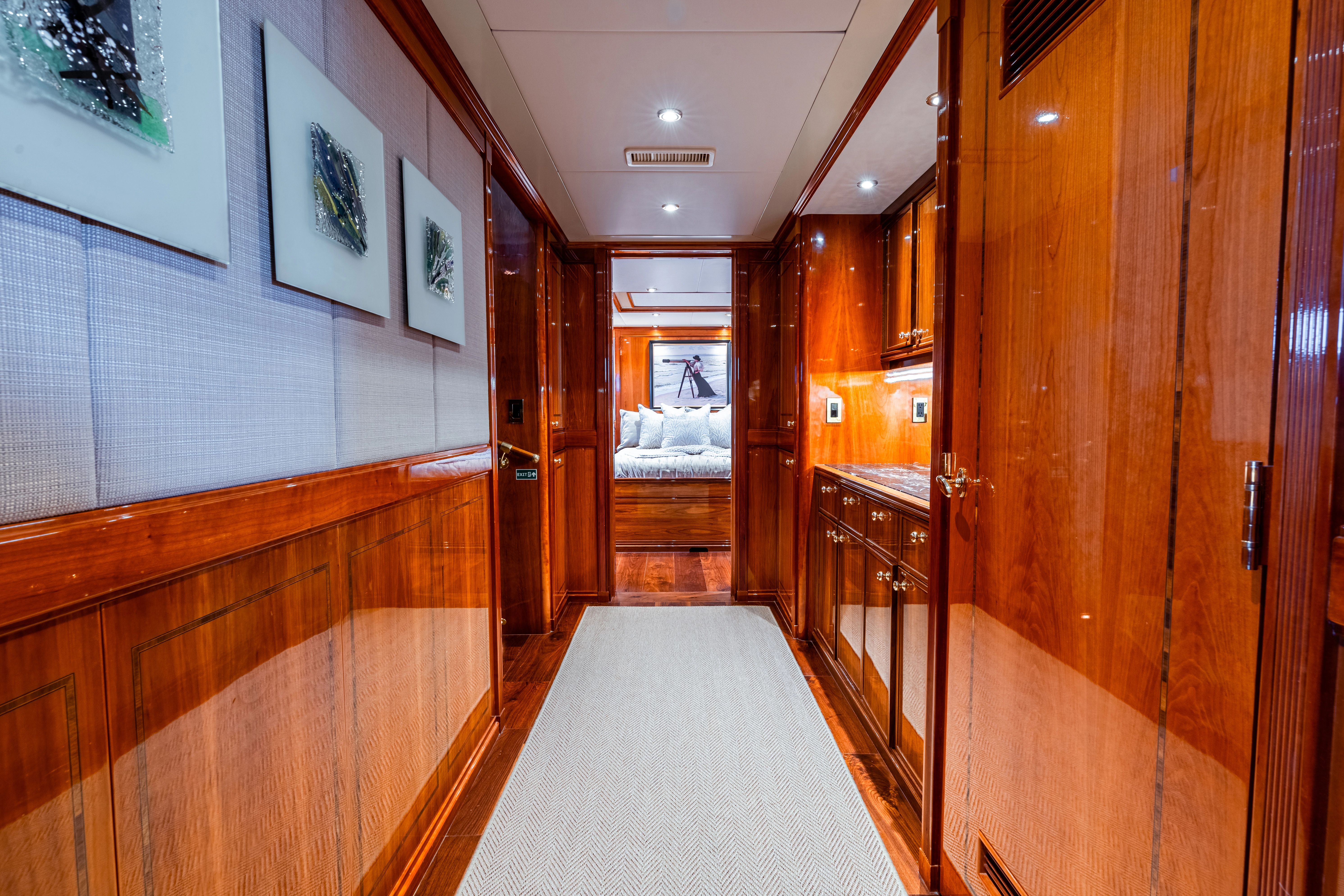 Luxurious hallway with wooden walls and carpeted floor, leading to a bedroom.
