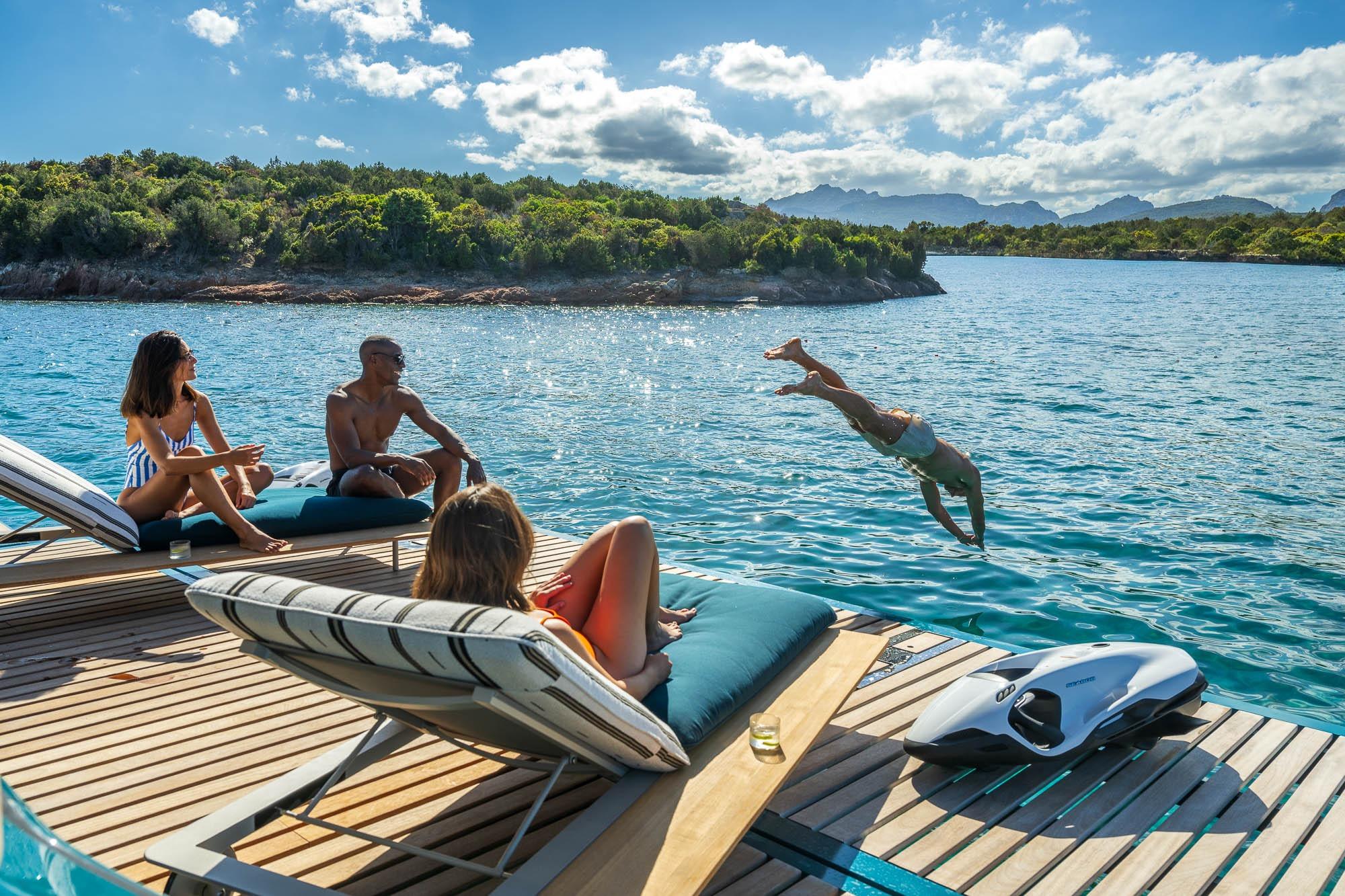 People relaxing on Lagoon Eighty 2 yacht, 2026, with one diving into the sea.