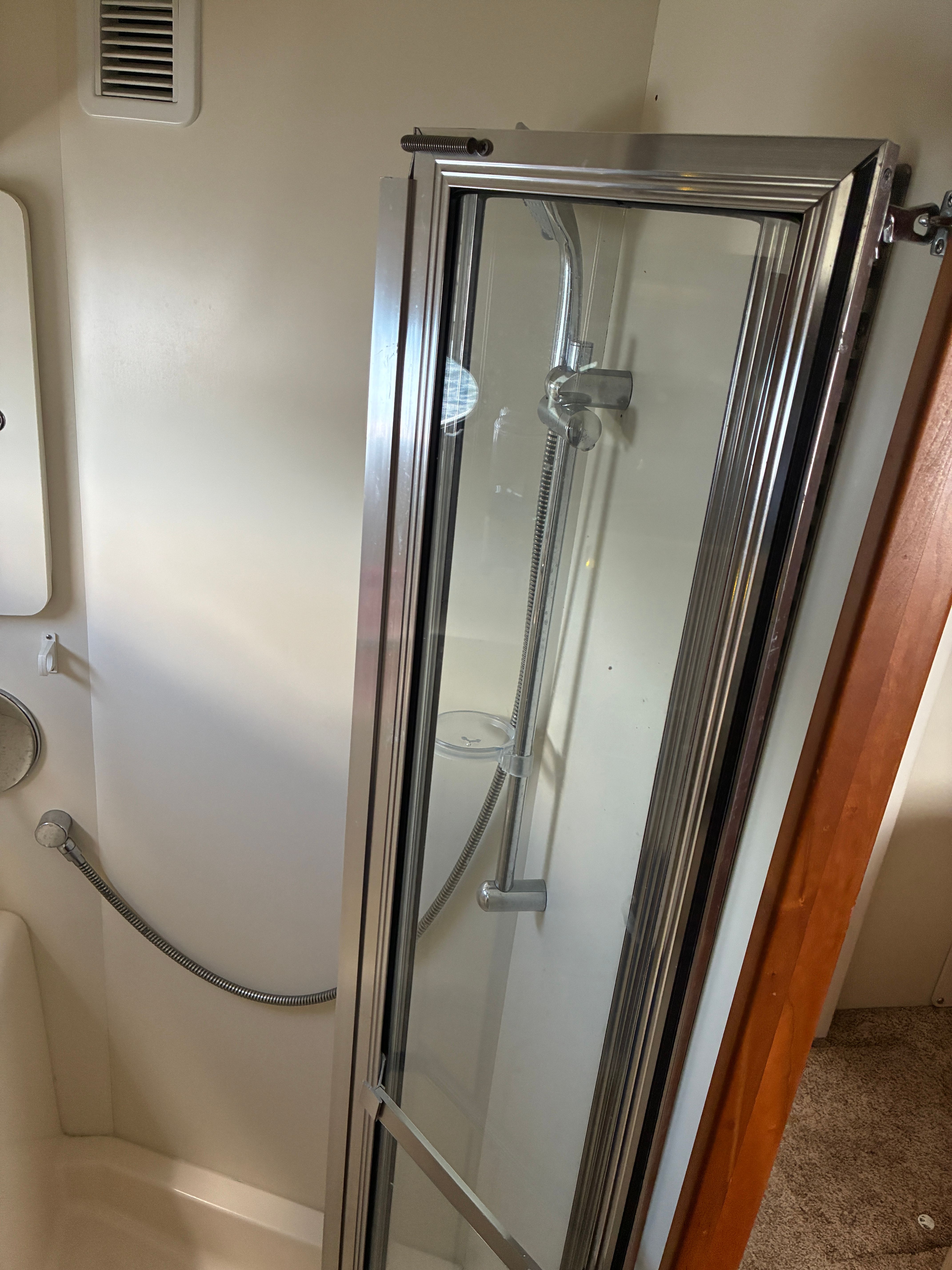 Shower cabin in a yacht with glass door and chrome fixtures.