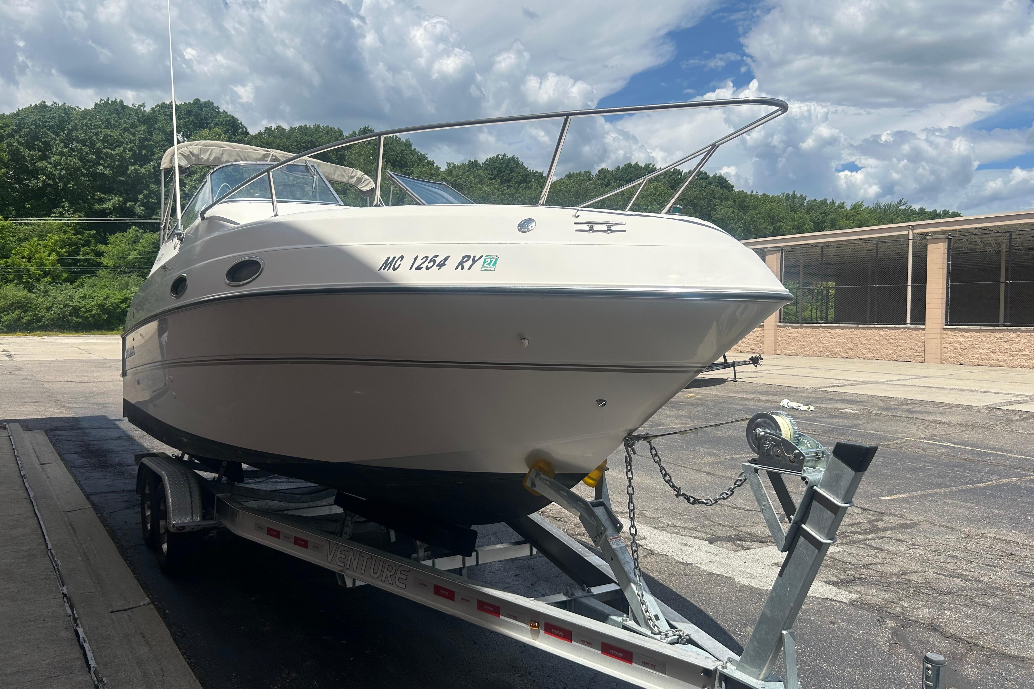 1998 Four Winns 258 Vista boat on trailer, parked outdoors under cloudy sky.