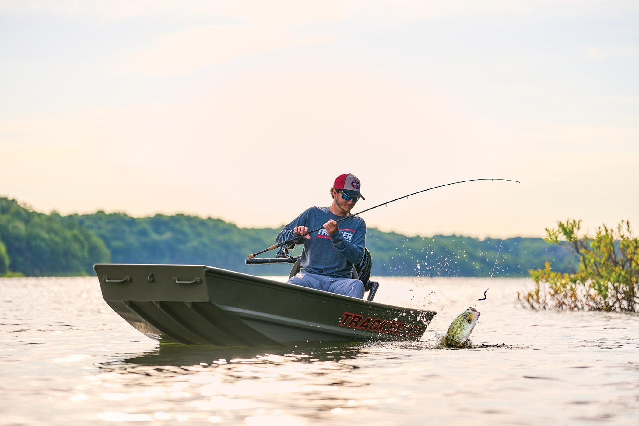 Man fishing from 2026 Tracker Grizzly 12 Jon boat on a serene lake.