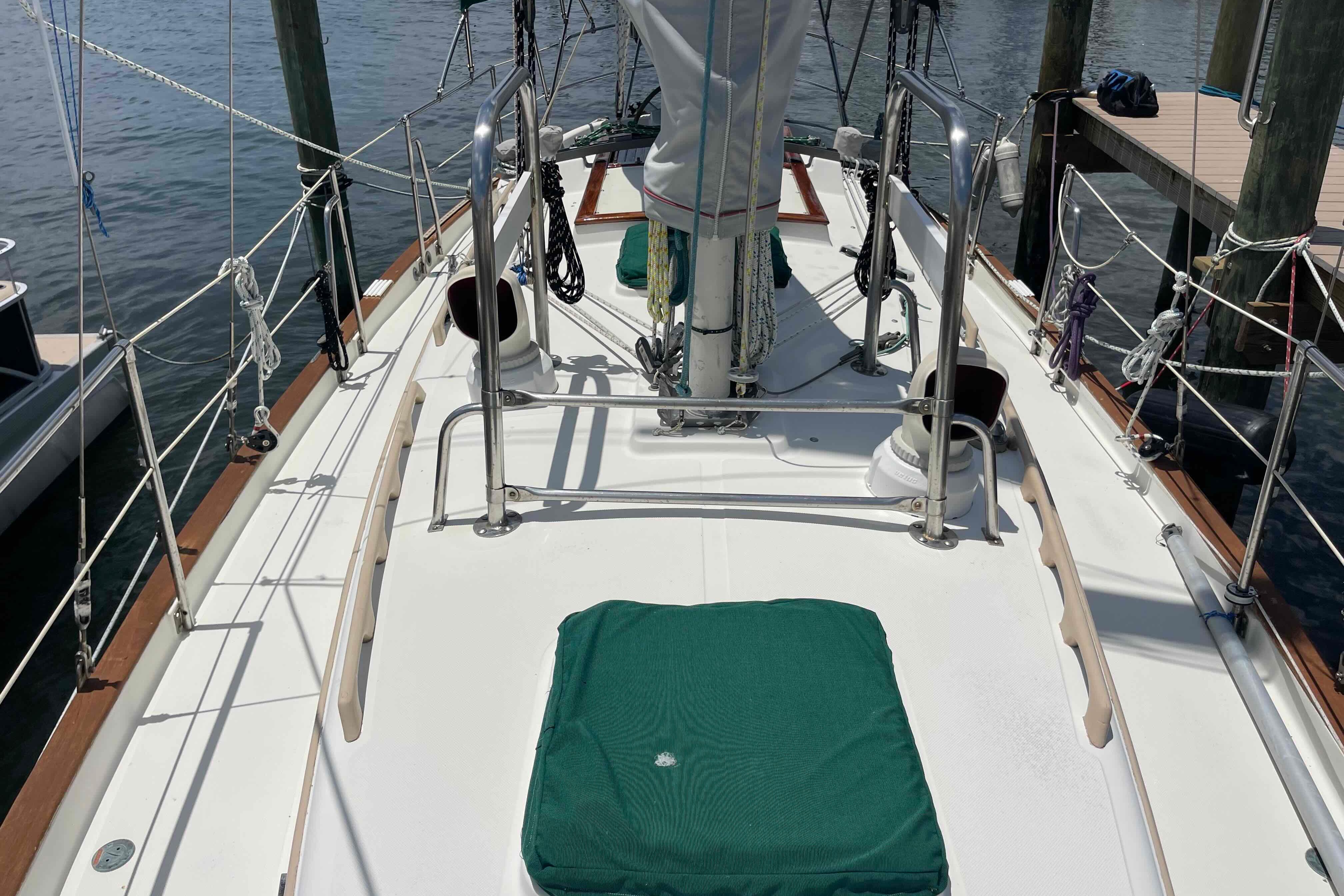 1987 Pacific Seacraft 34 sailboat deck with green cover, docked at marina.