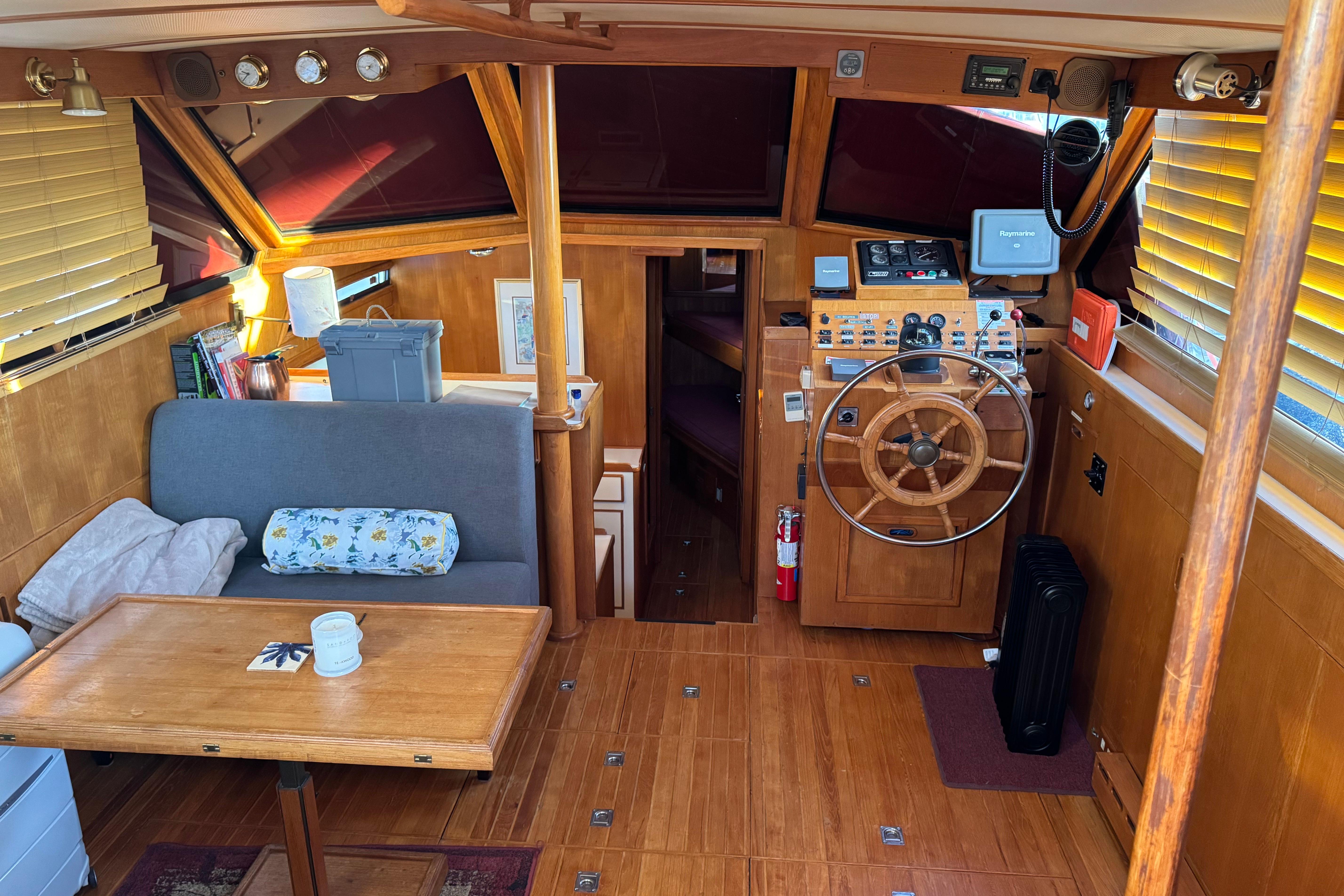 Cozy interior of a 1987 President 37 yacht with wooden helm and seating area.