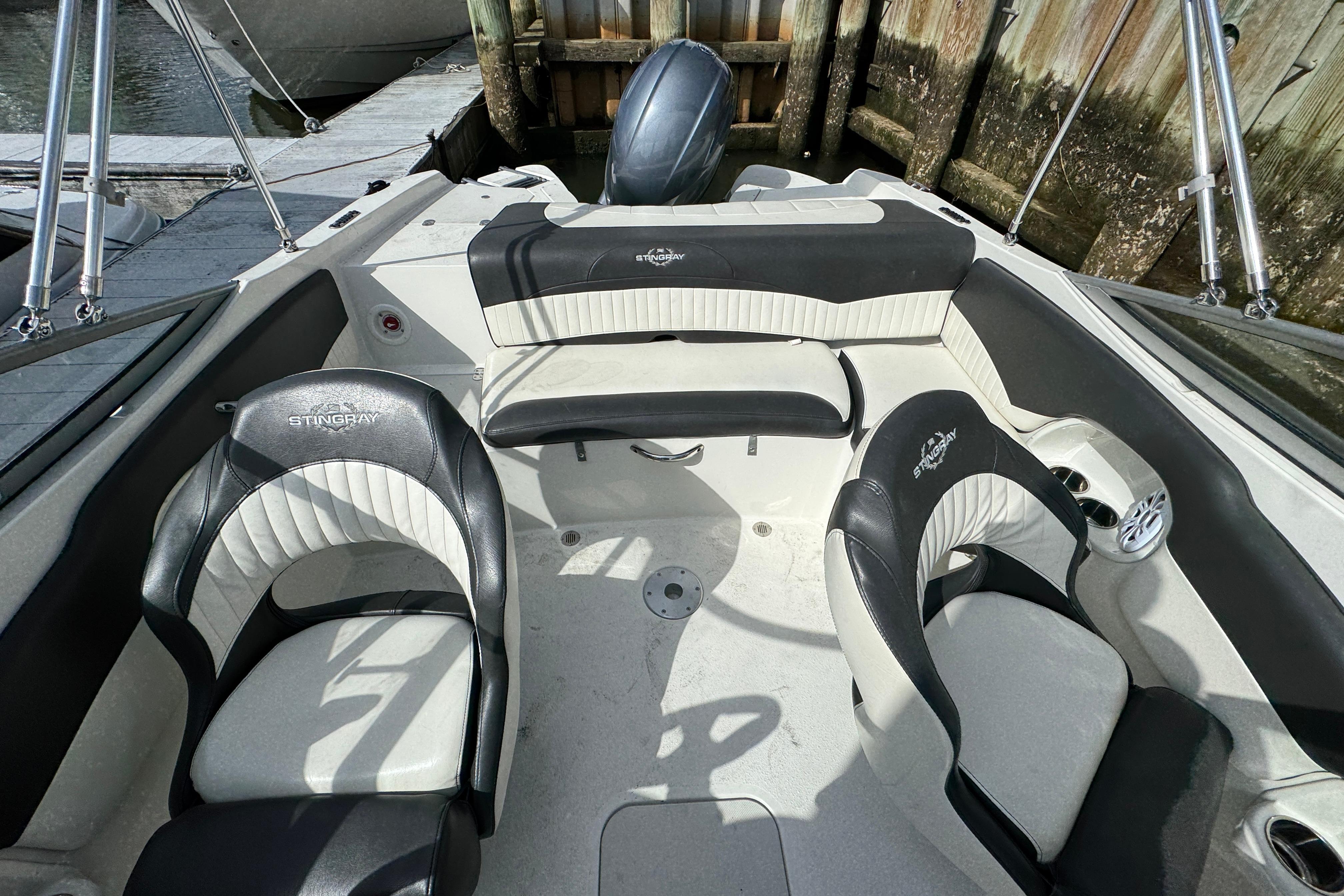 2019 Stingray 204 LR boat interior with black and white seating, docked by wooden pier.