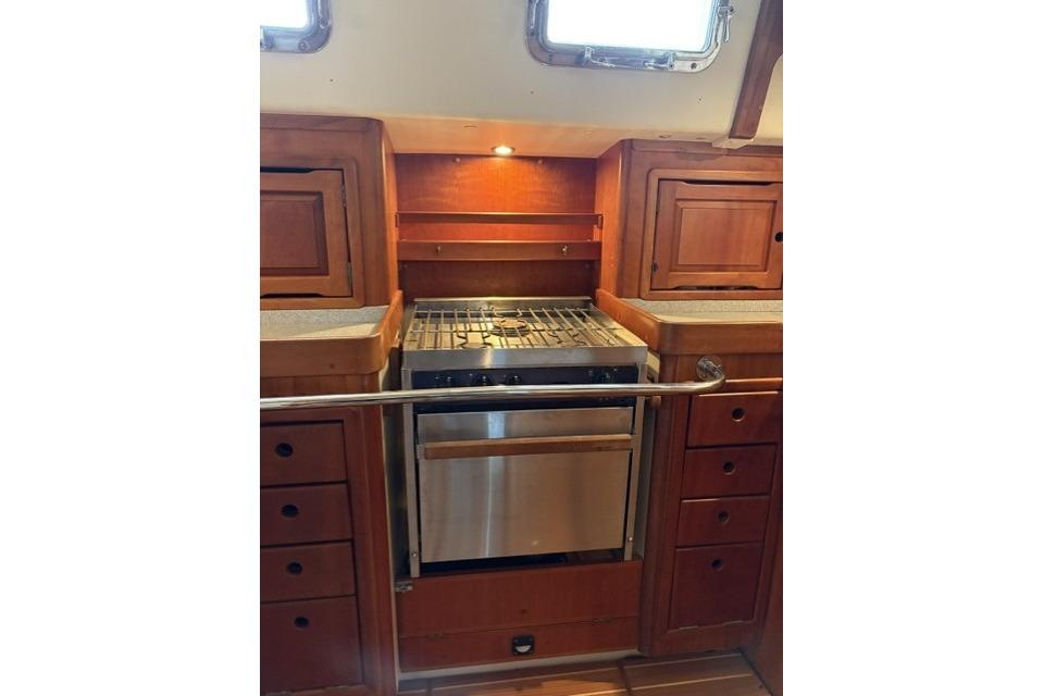 2002 Saga 43 yacht kitchen with wooden cabinetry and stainless steel stove.