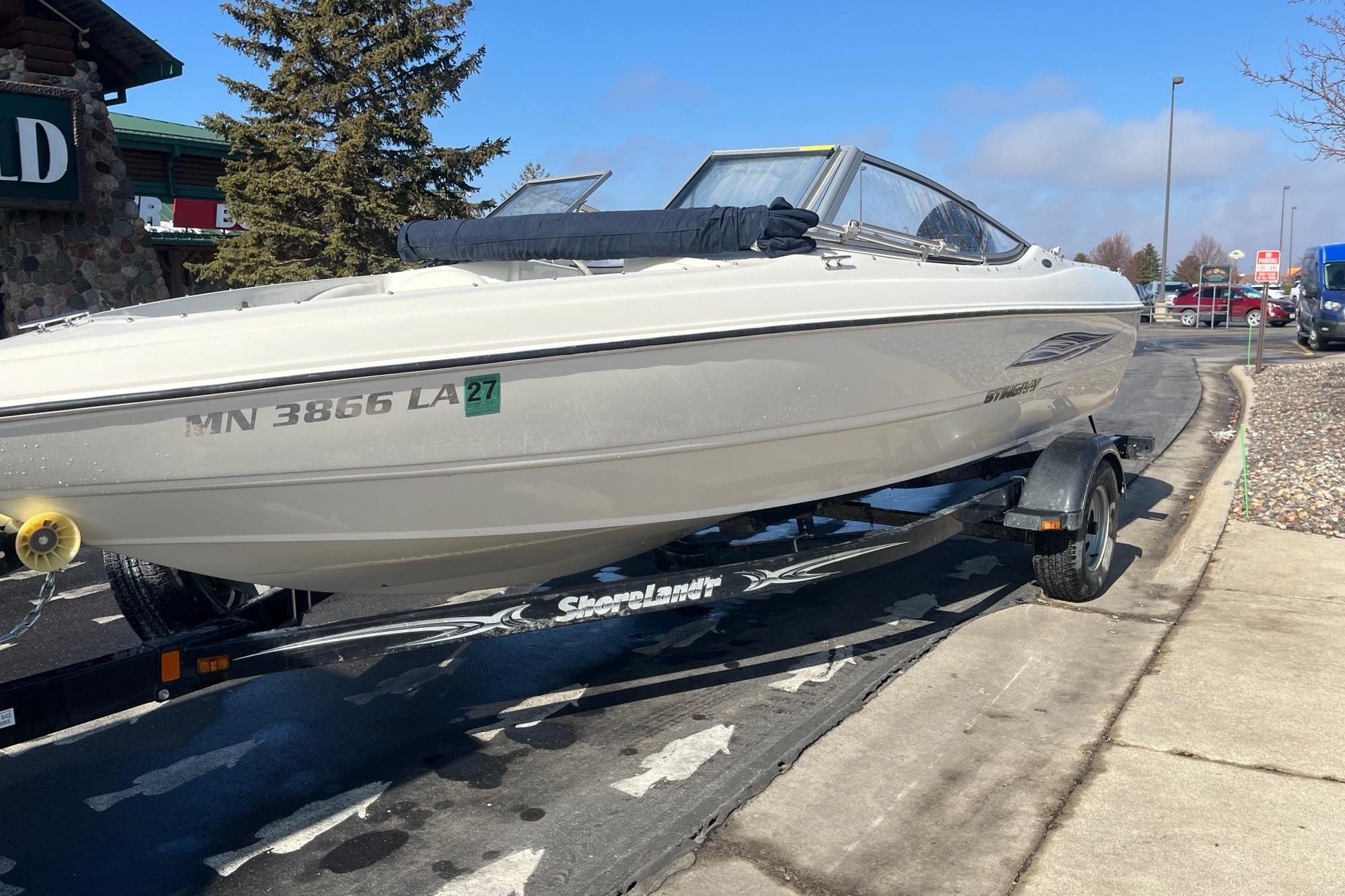 2013 Stingray 191 RX boat on trailer, parked outdoors near a building.