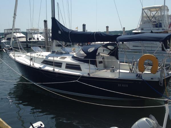 Sailboat in harbor with blue cover and lifebuoy at the stern.