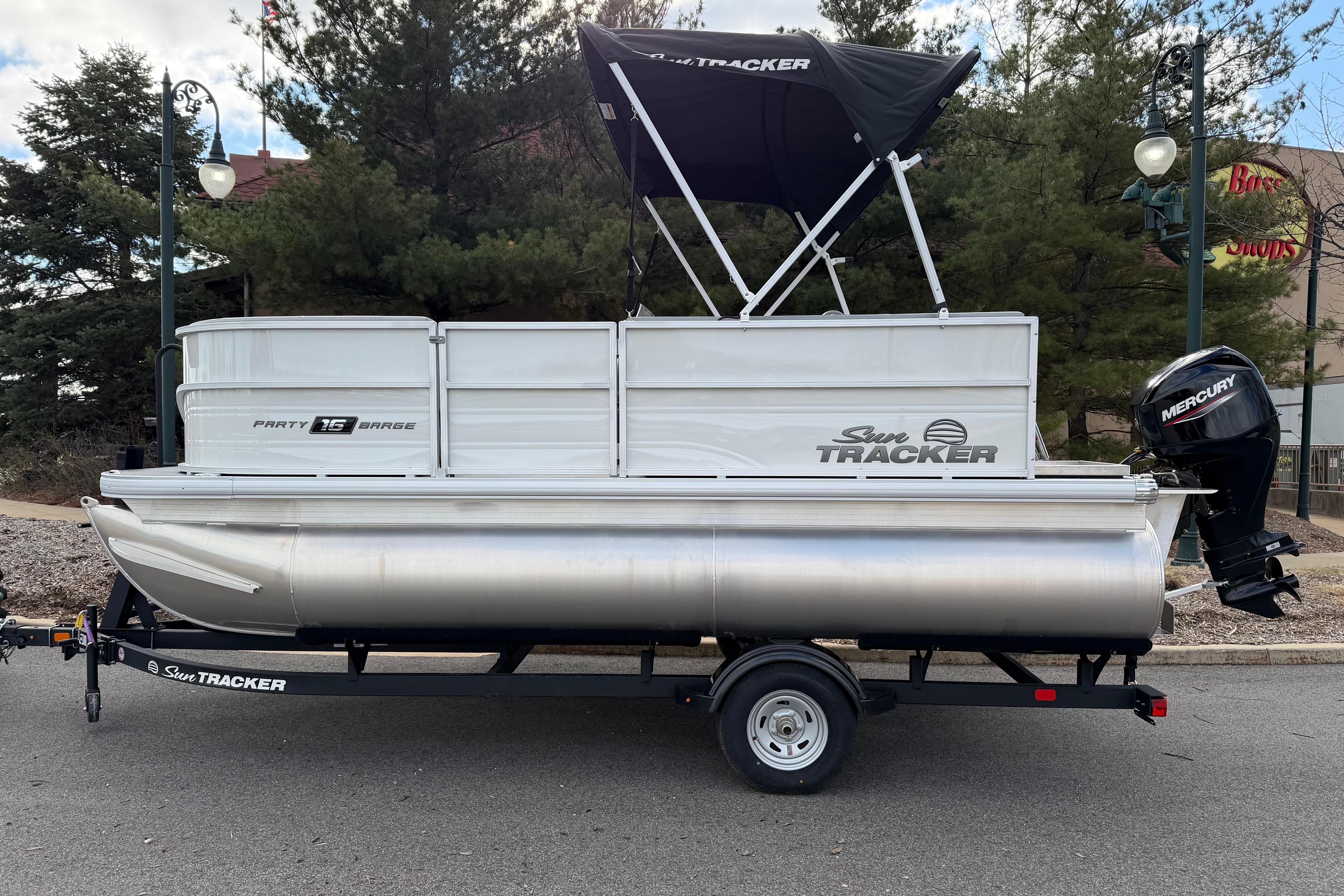 2026 Sun Tracker Party Barge 16 DLX pontoon boat on trailer, parked outdoors.
