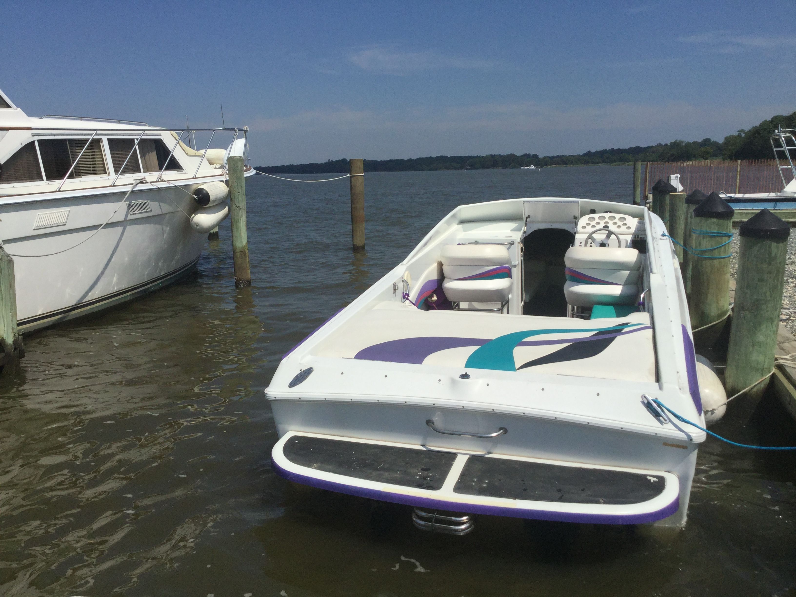 A 1995 Baja Caliber docked. It features a colorful design and white seating.