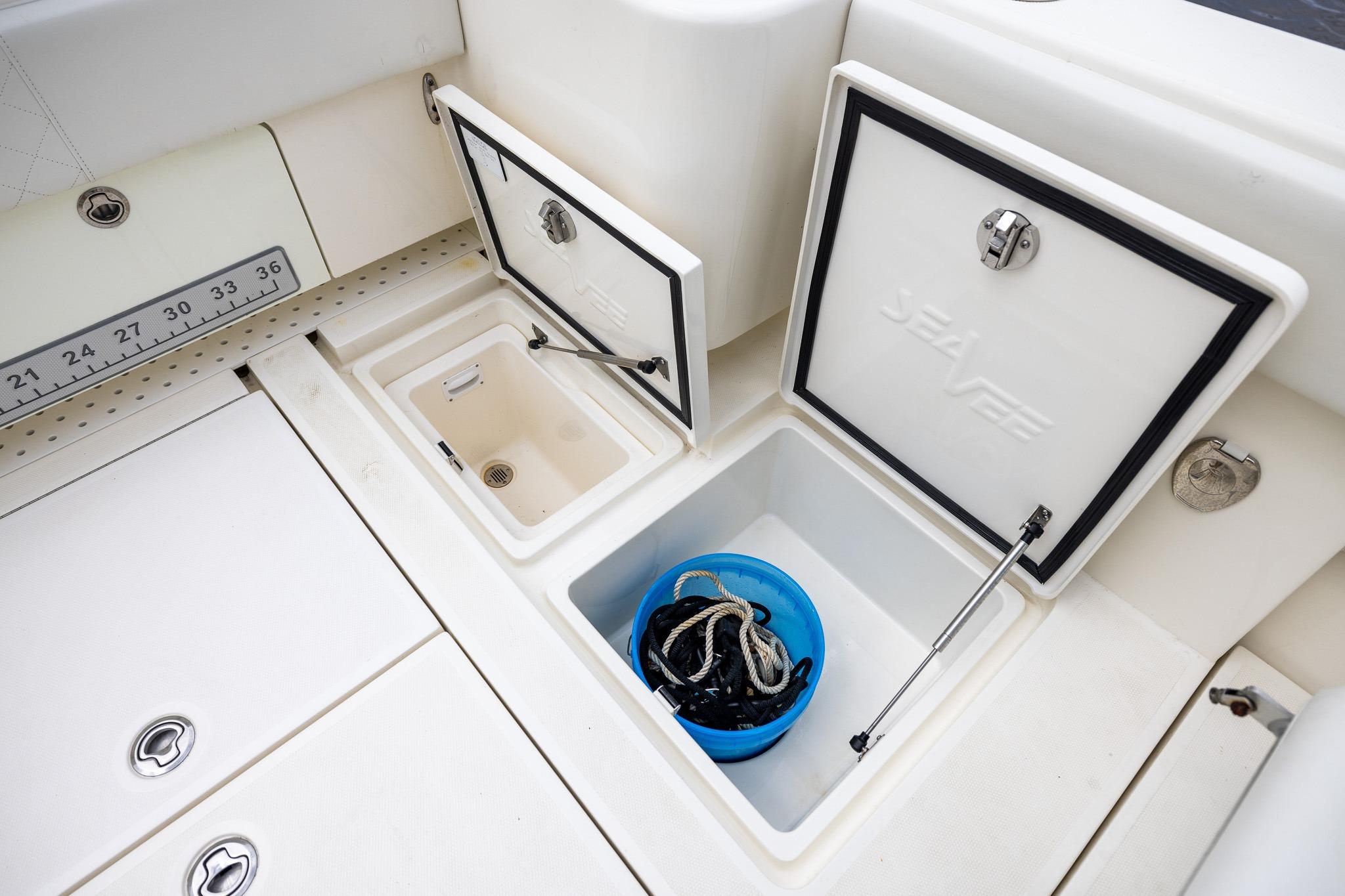 2019 SeaVee 322Z boat storage compartments with open hatches and a blue bucket inside.