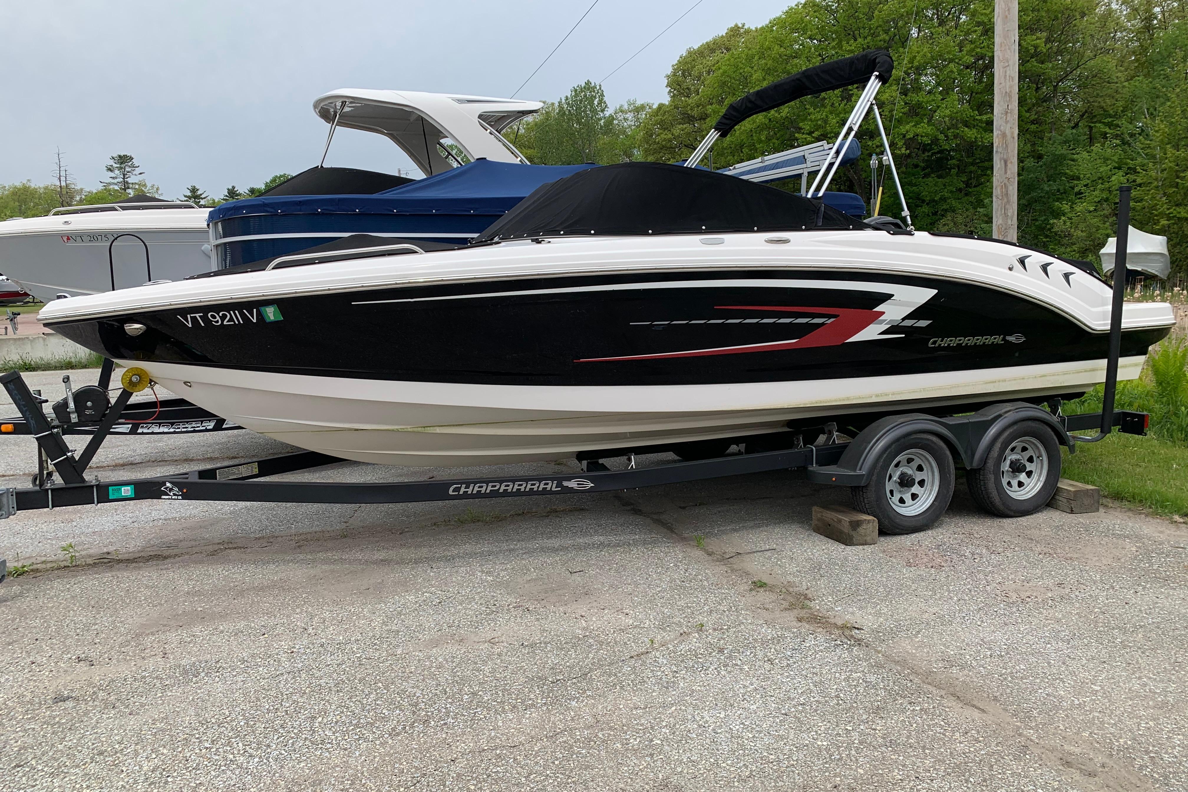 2022 Chaparral 23 SSi boat on trailer, black and white design, parked outdoors.