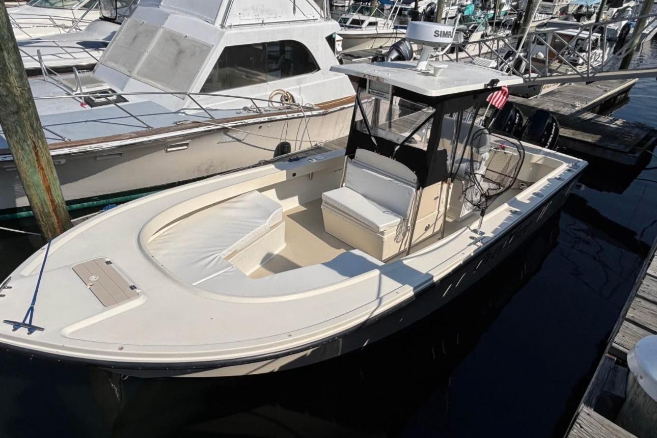 1999 Parker 2501 Center Console boat docked at marina, featuring spacious seating and modern equipment.