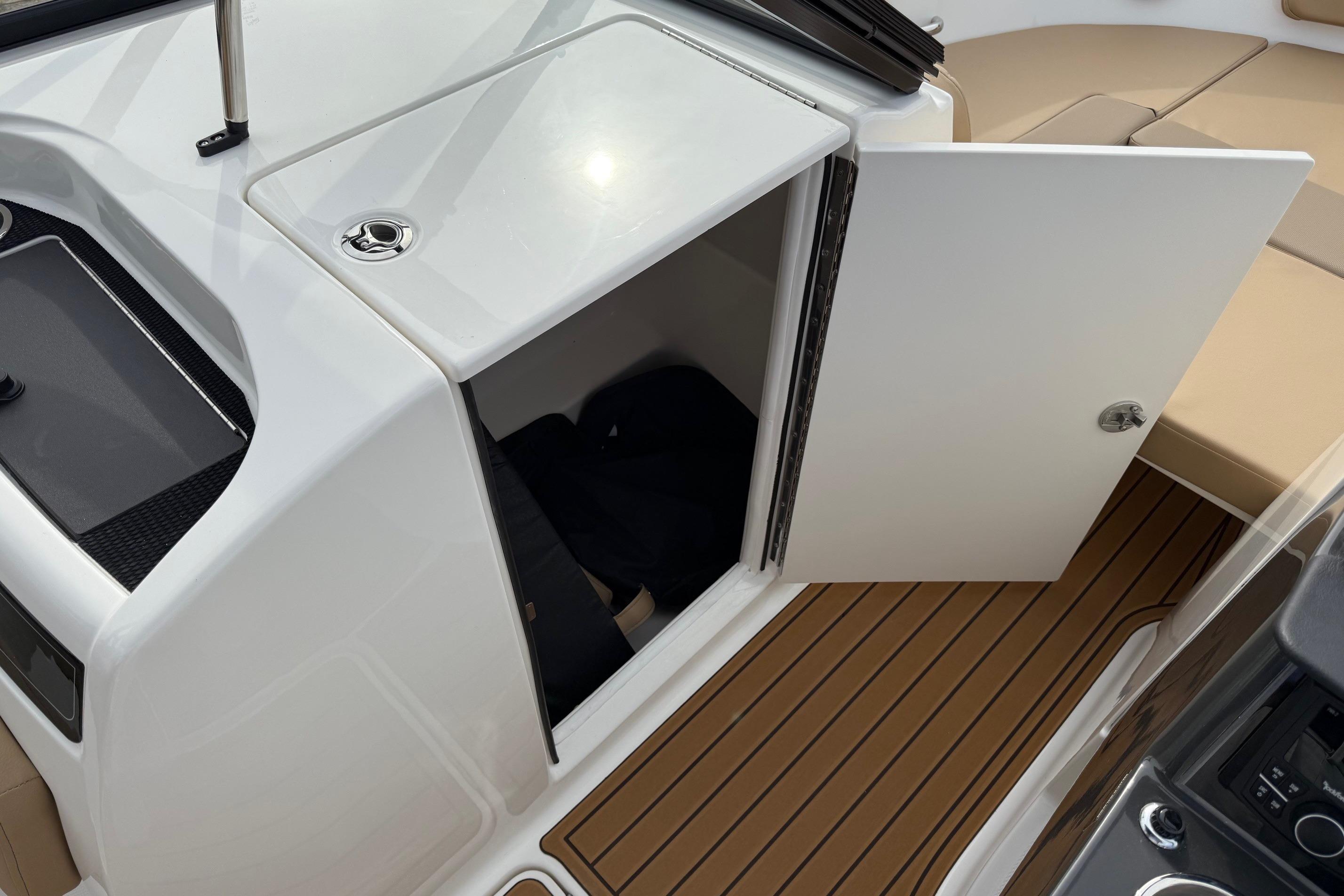 2026 Bayliner VR6 Bowrider OB interior storage compartment with open door and teak flooring.