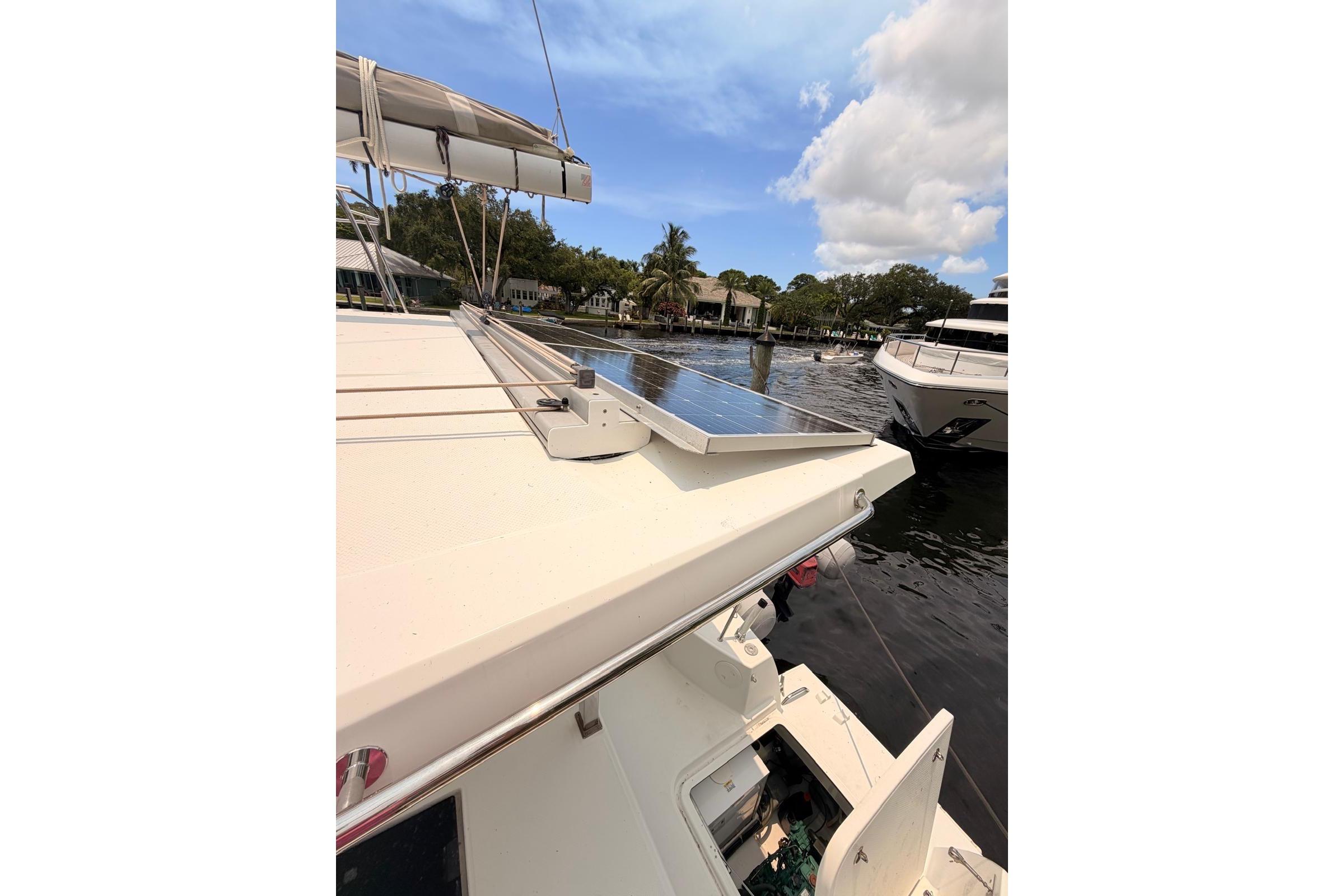 2018 Fountaine Pajot Lucia 40 catamaran with solar panels, docked in a scenic marina.