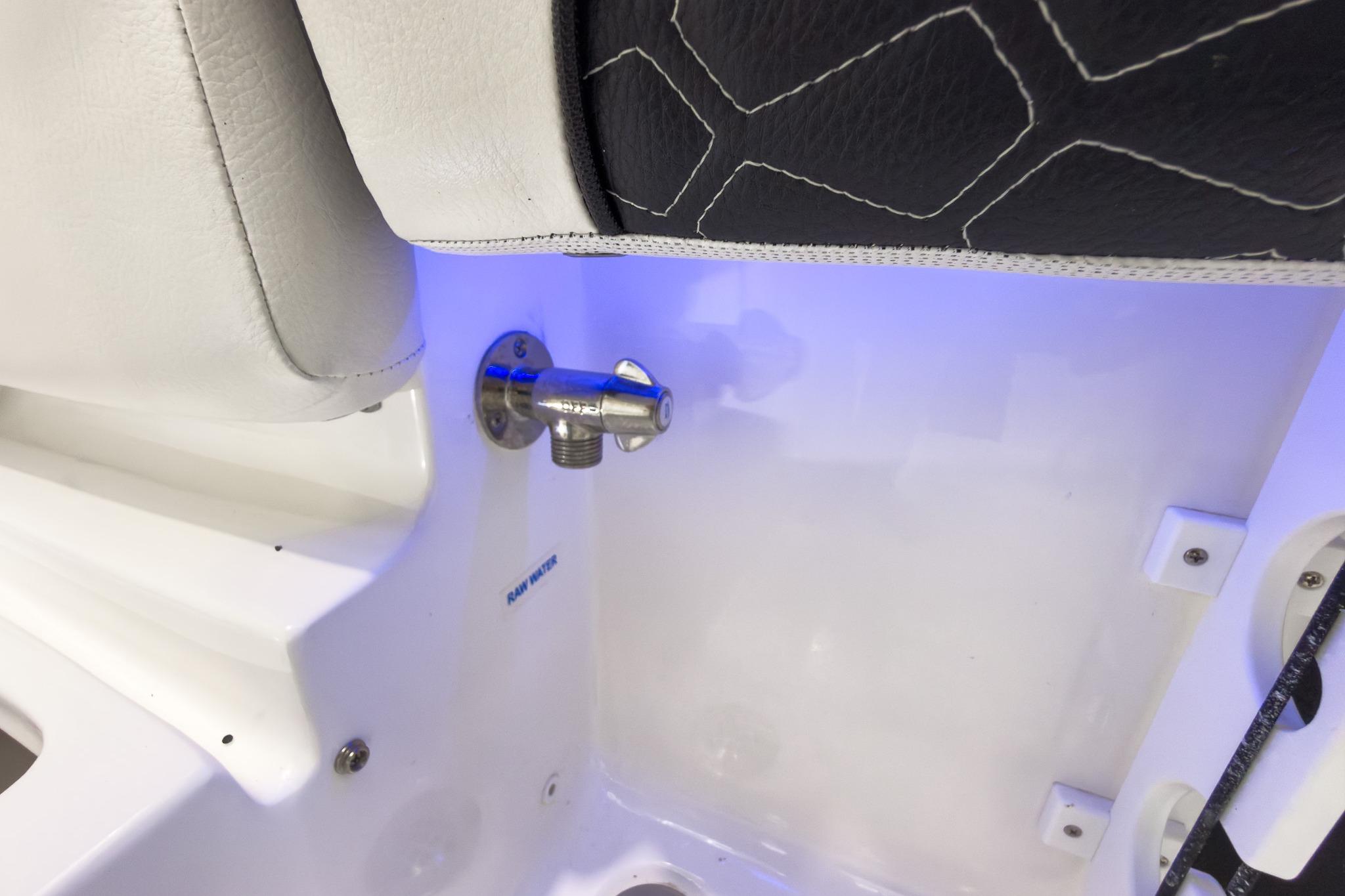 Close-up of a boat interior with white and black upholstery and blue lighting.