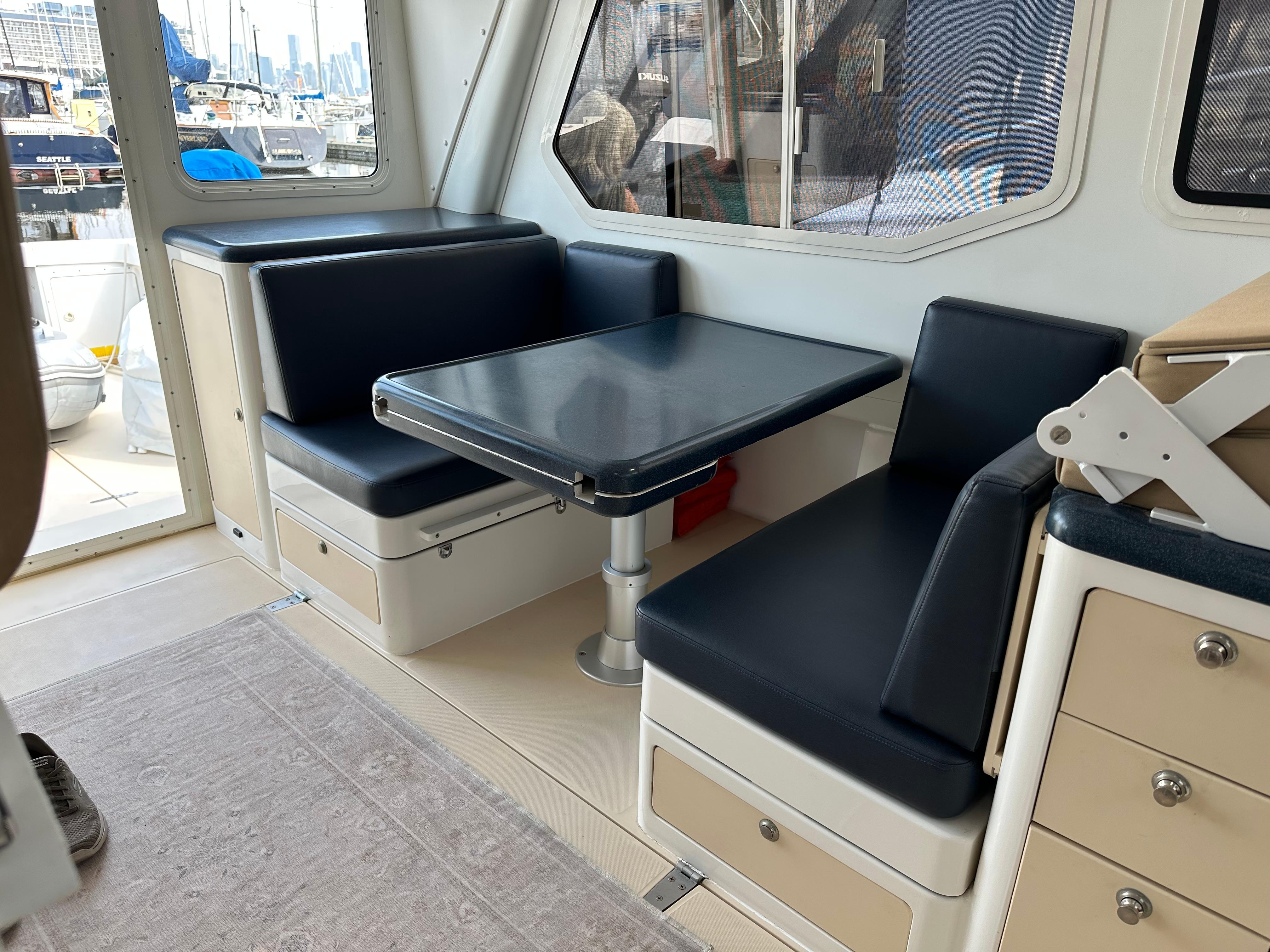 Interior of 2002 True North 38 boat with blue seating and table.