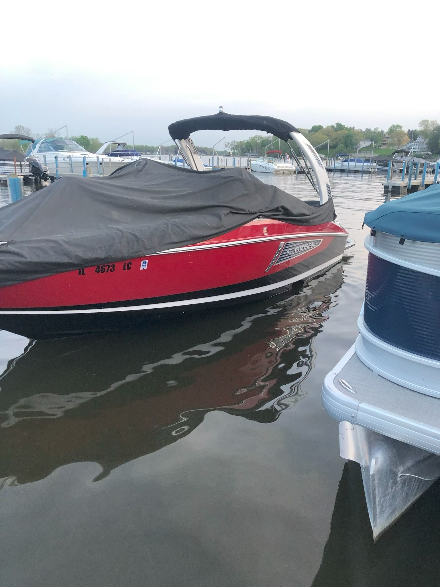 Red 2019 Regal 25 RX Surf boat docked on water.